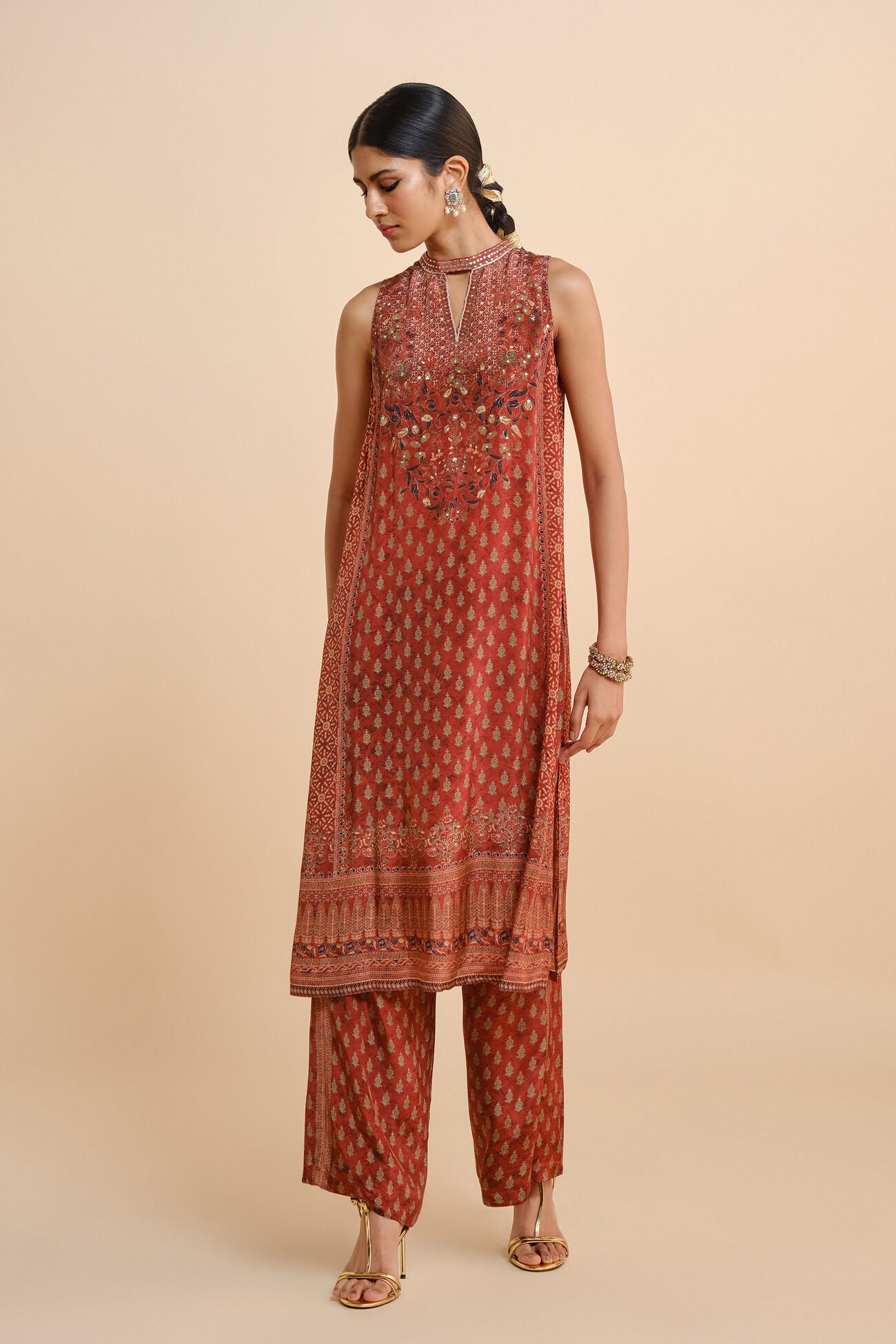 Woman wearing a red patterned kurta with palazzo pants on a beige background