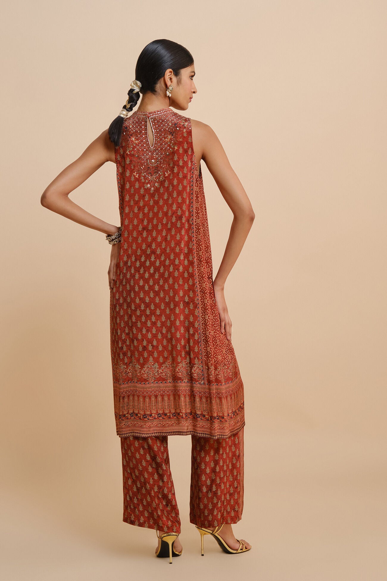 Woman wearing a traditional outfit with intricate patterns on a beige background