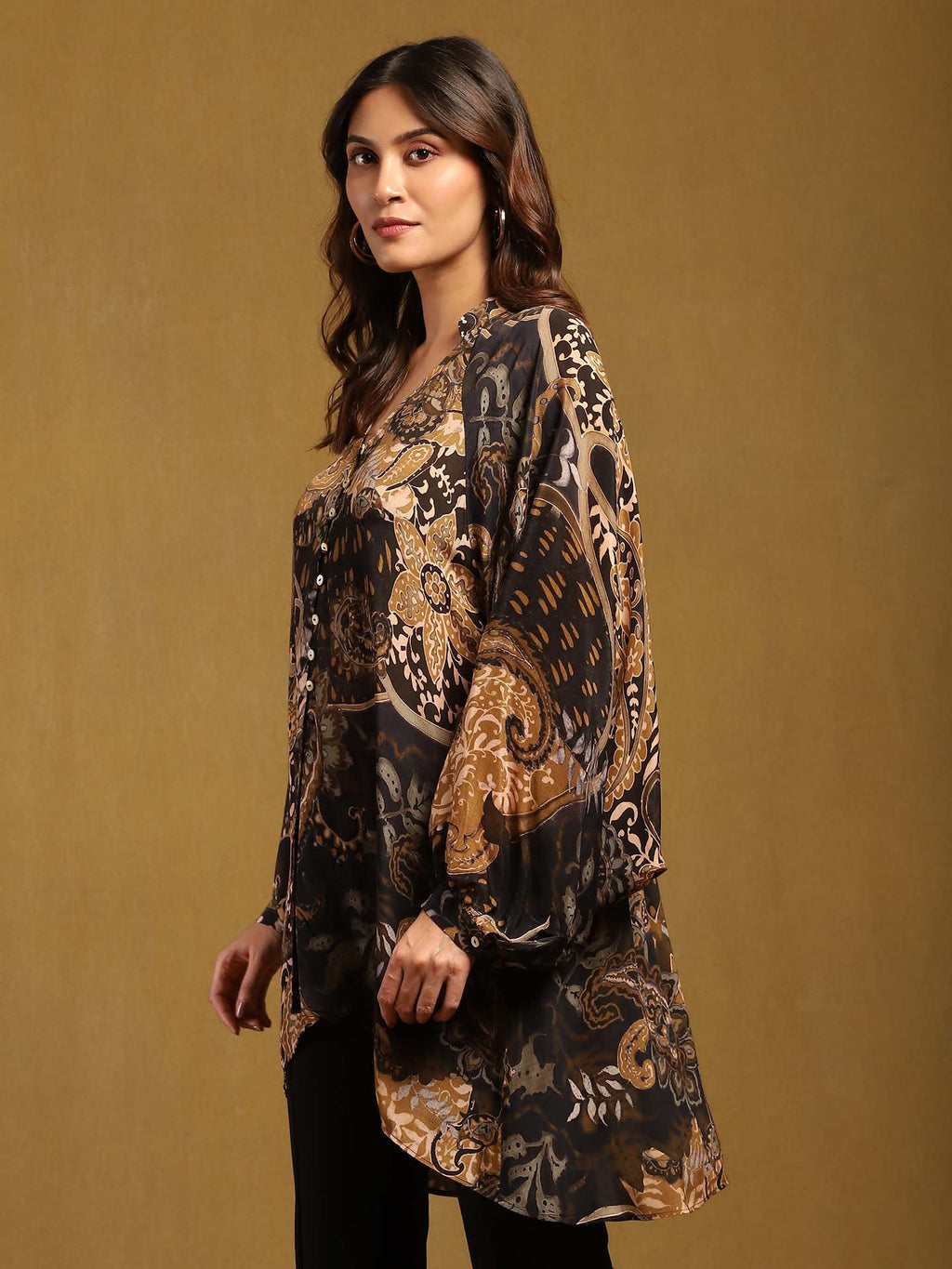 Woman wearing a patterned long-sleeve top against a brown background