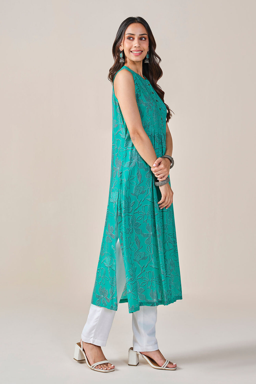 Woman wearing a teal kurta with white pants on a beige background