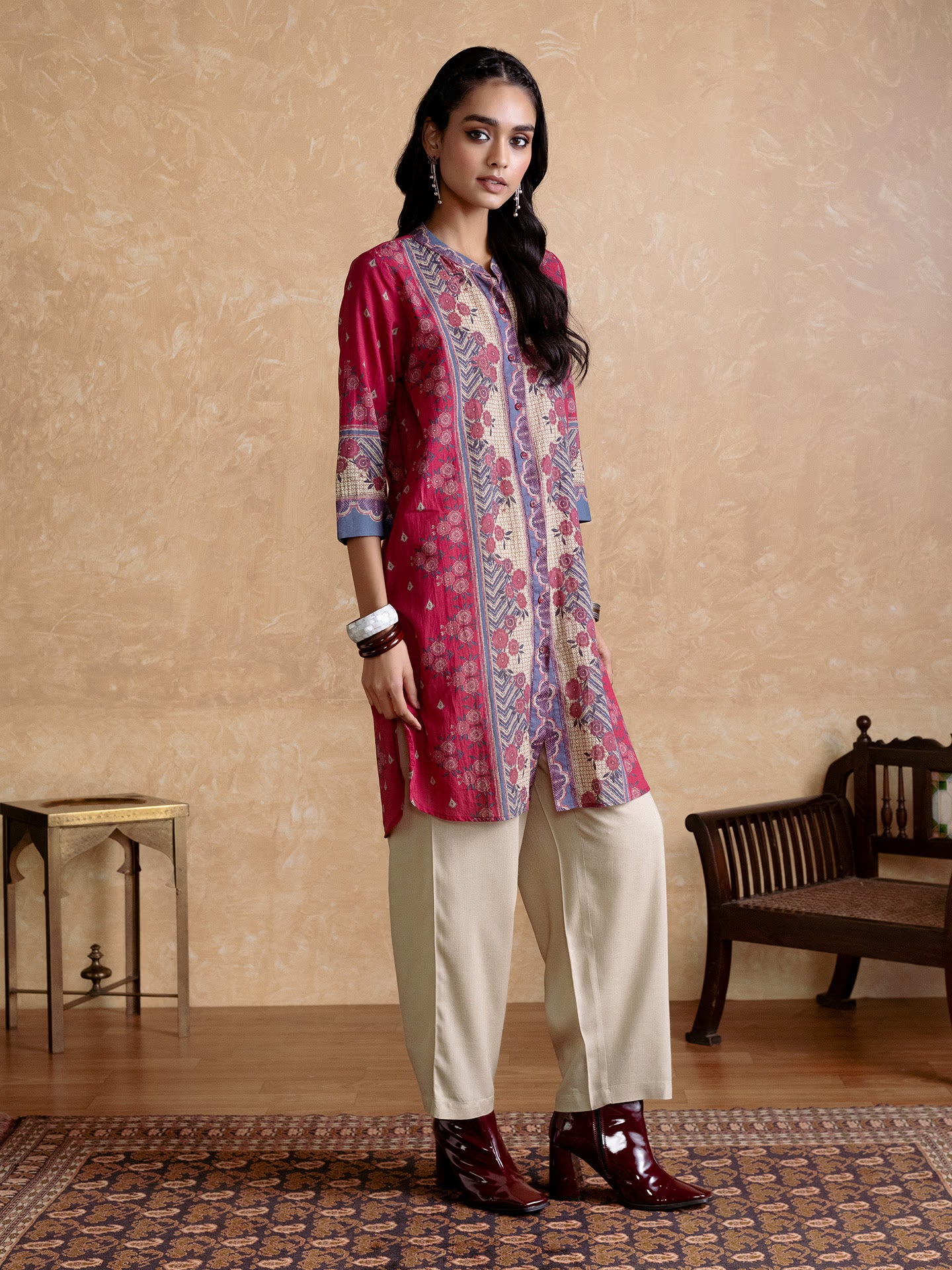 Woman wearing a patterned kurta with beige pants in a room setting.