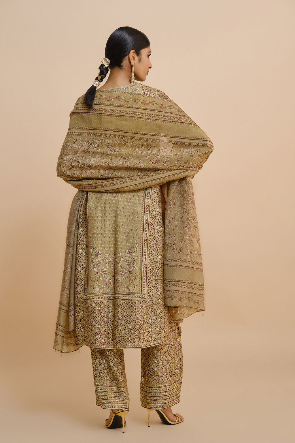 Woman wearing a traditional outfit with a beige shawl on a beige background