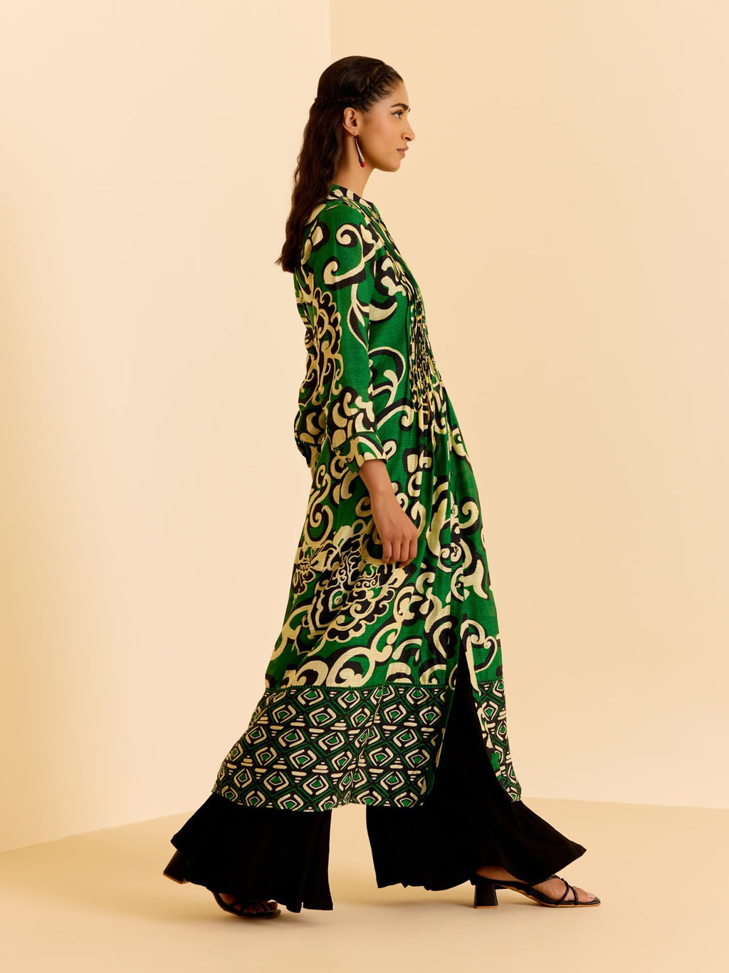 Woman wearing a green patterned dress on a beige background