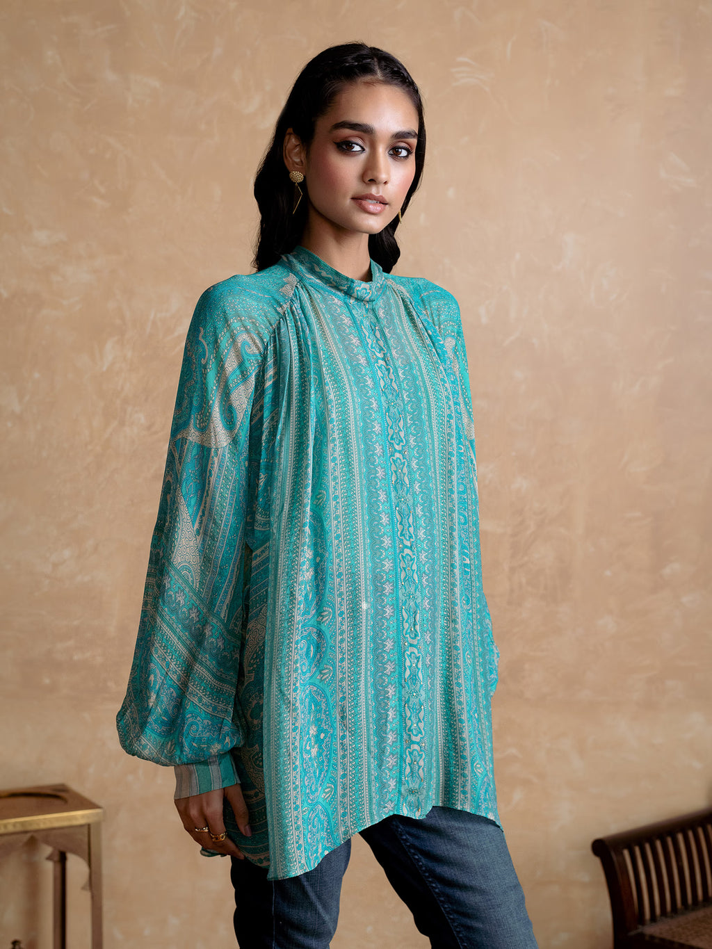 Woman wearing a Blue patterned shirt against a beige background
