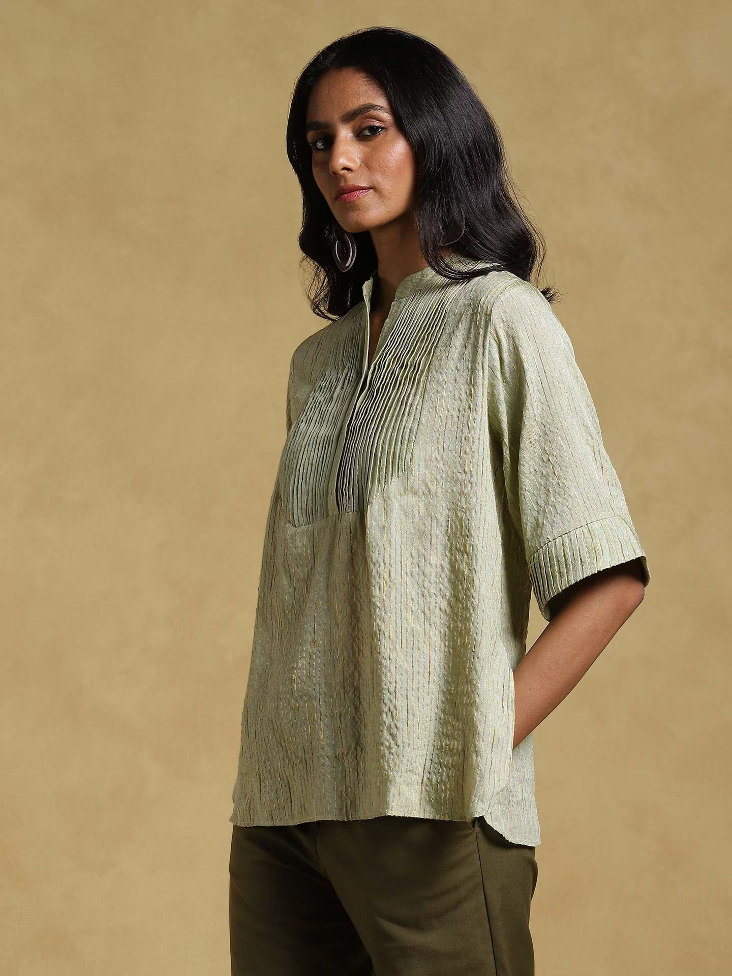 Woman wearing a light green textured blouse with a beige background