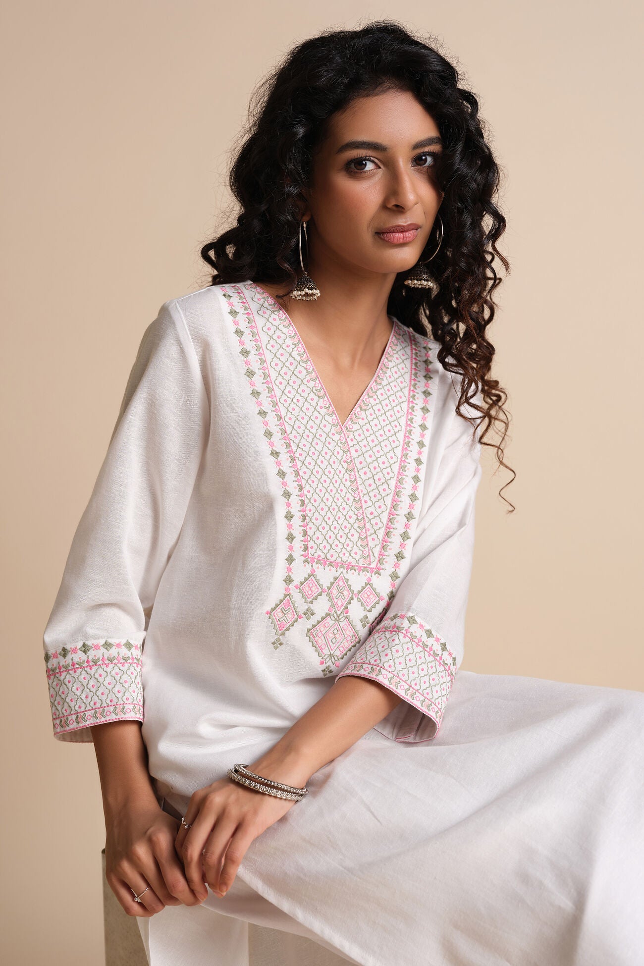 Woman wearing a white embroidered traditional outfit on a beige background