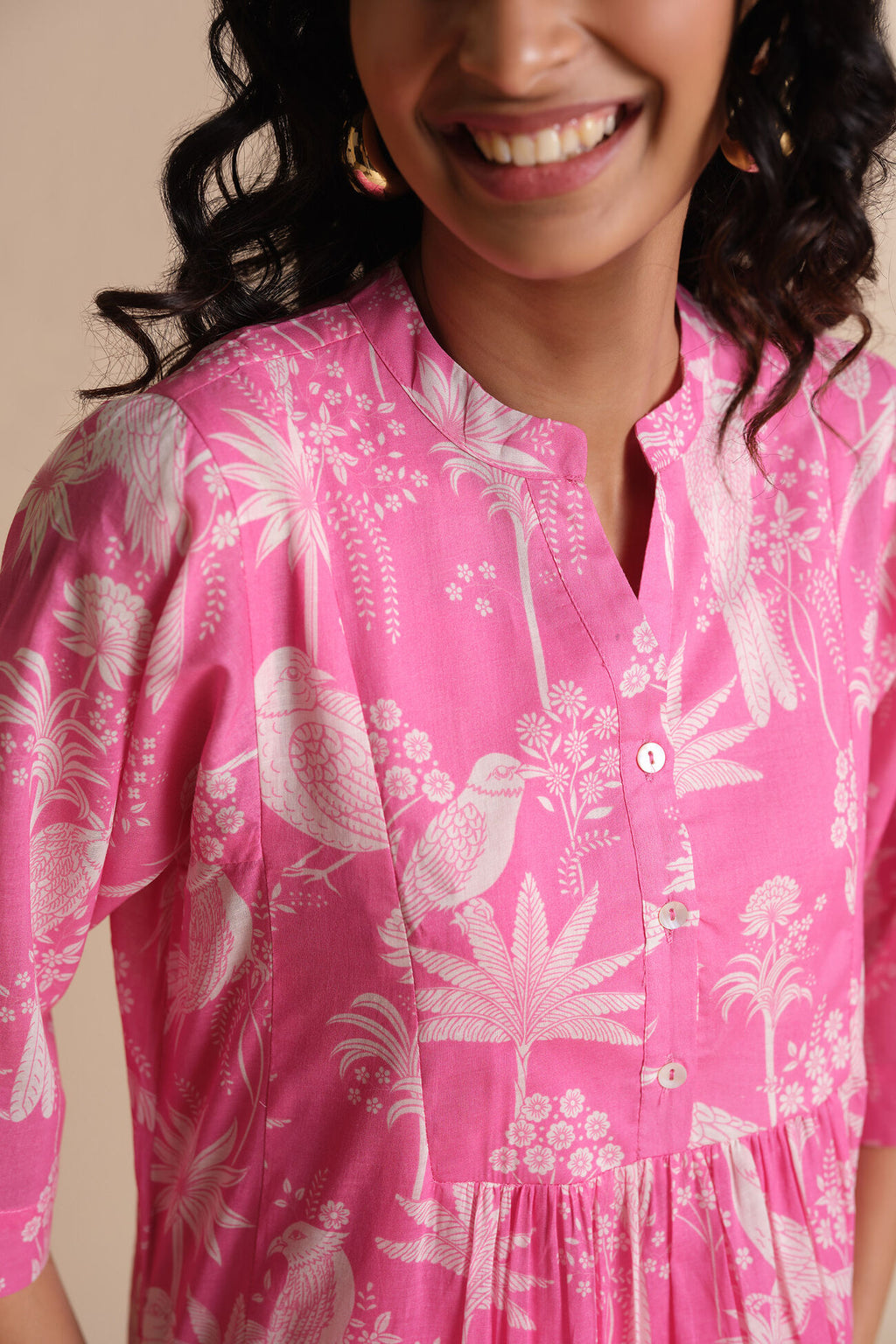 Person wearing a pink dress with white floral and bird pattern