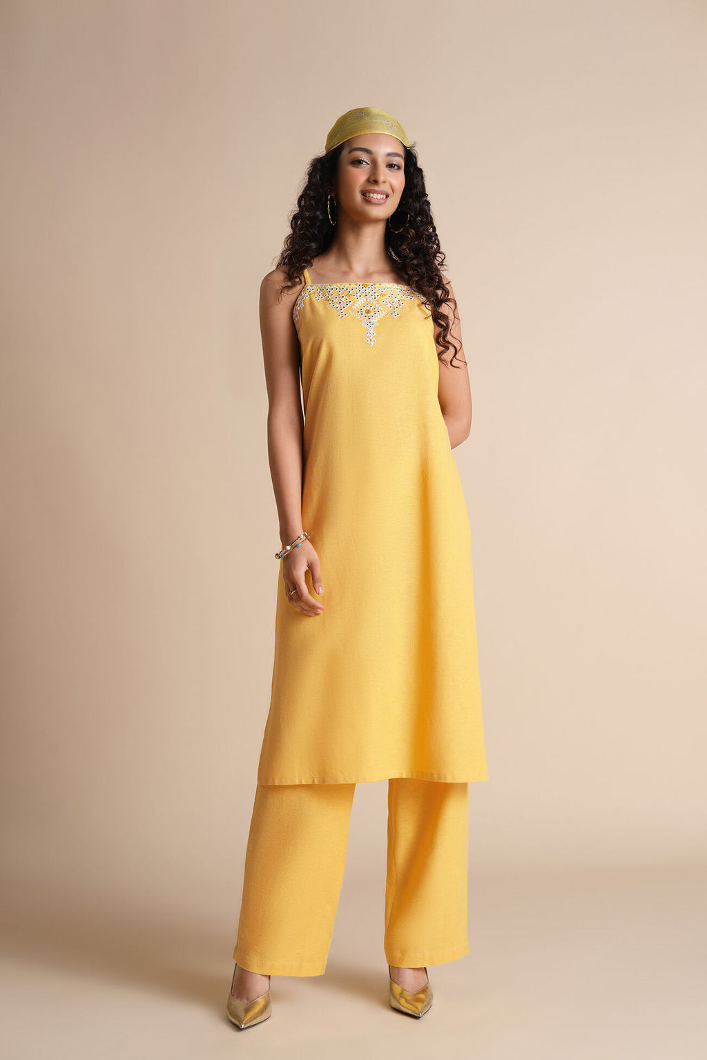 Woman wearing a yellow outfit with a plain background