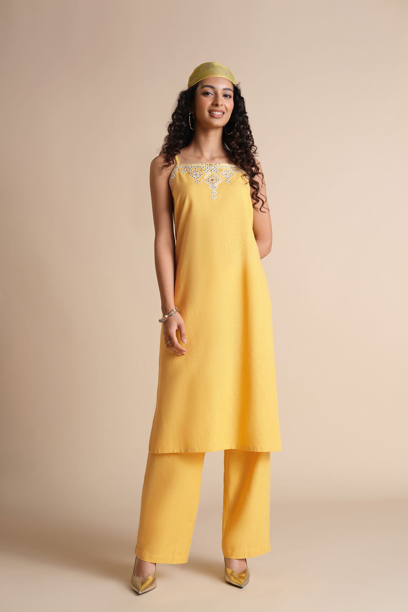 Woman wearing a yellow outfit with a plain background