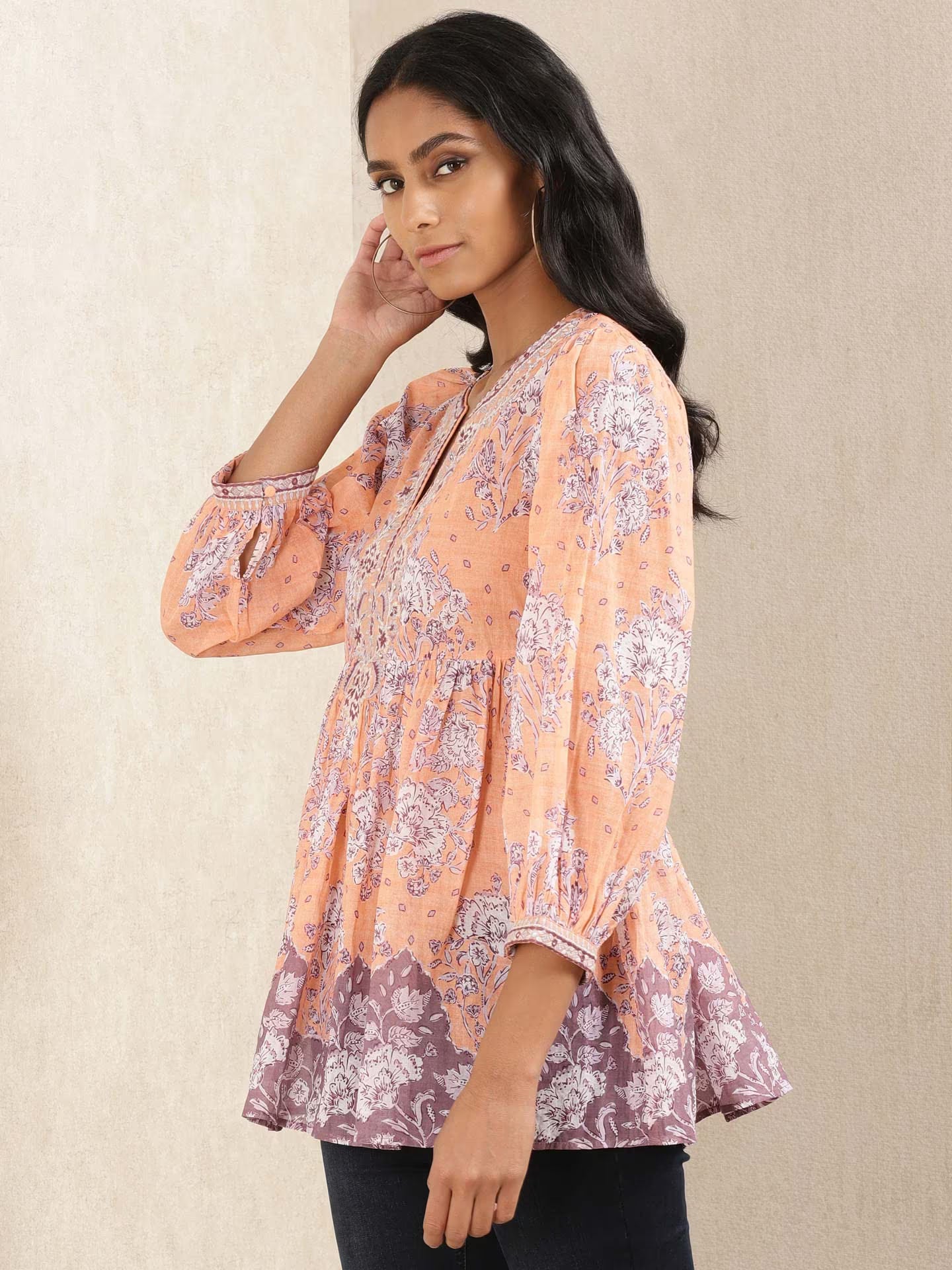 Woman wearing a floral kurta against a beige background