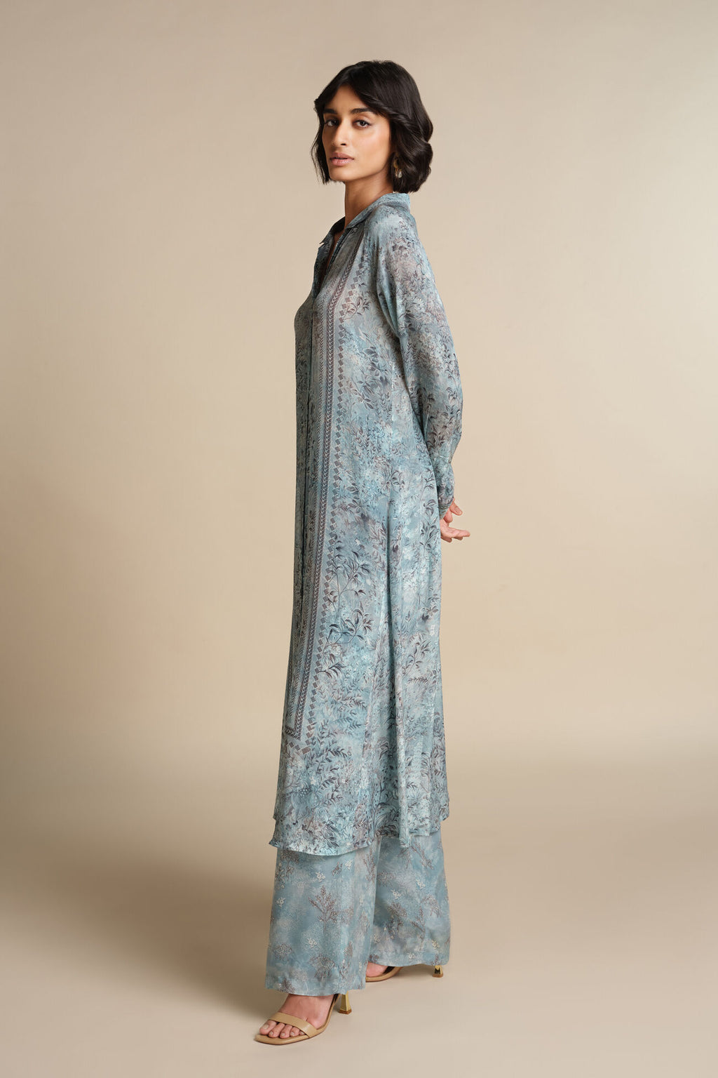 Woman wearing a long, light blue floral dress against a beige background