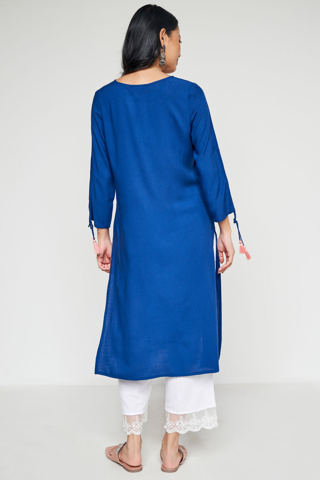 Woman wearing a blue kurta with white pants on a white background