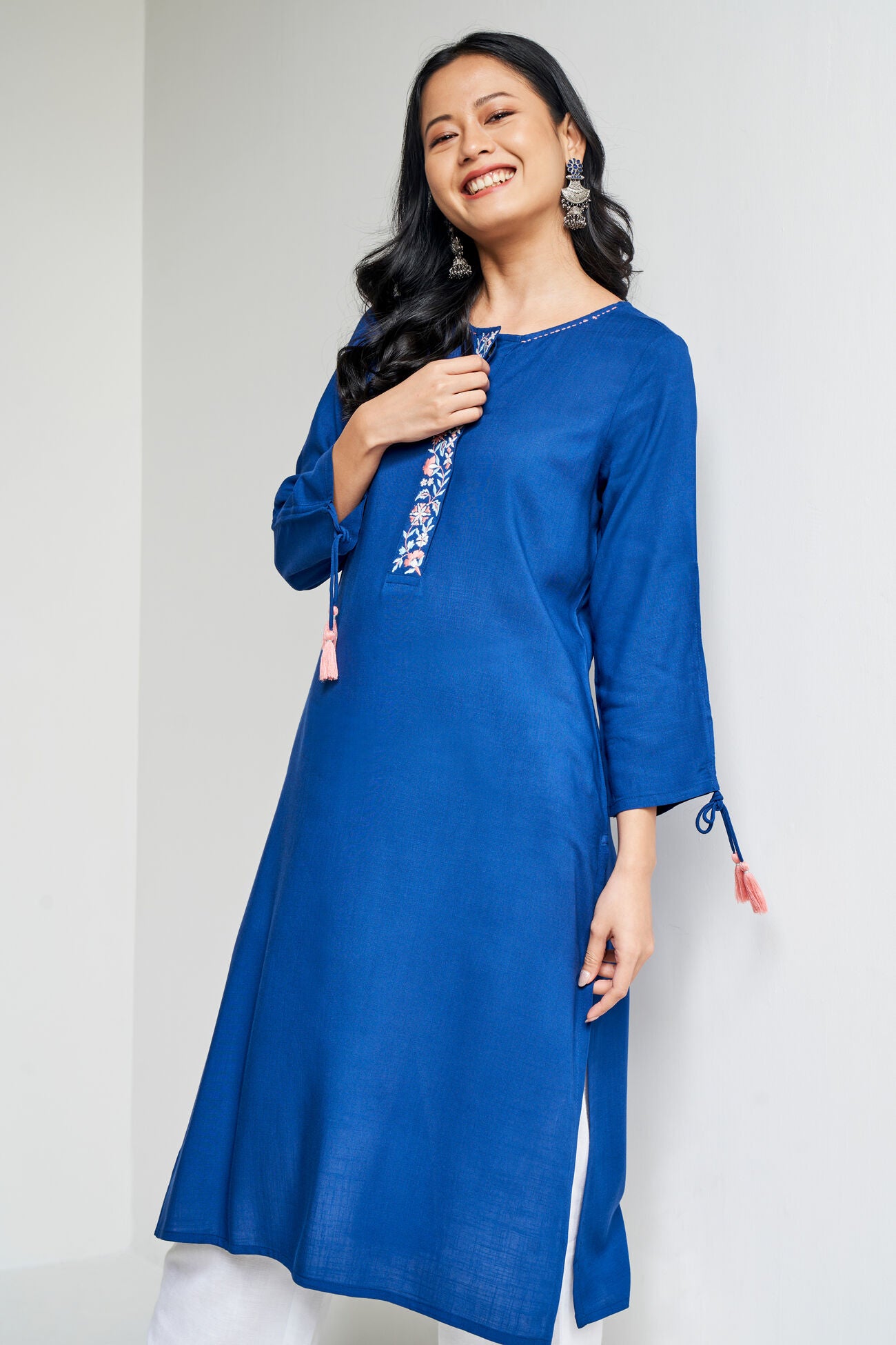 Woman wearing a blue kurta with white embroidery on a white background