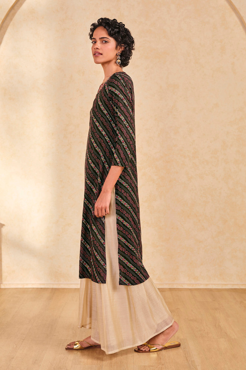 Woman wearing a black and white patterned kurta with beige pants against a beige background