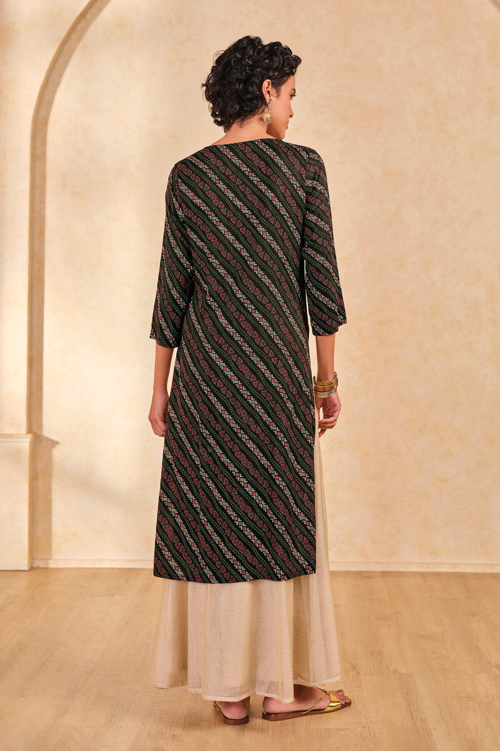 Woman wearing a black and white striped kurta with a beige skirt in an indoor setting.