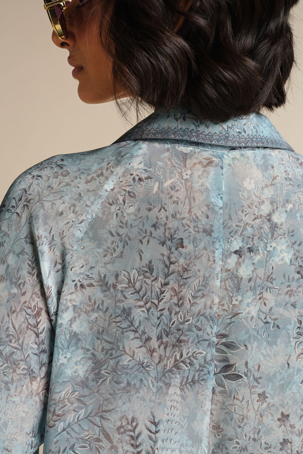 Close-up of a person wearing a floral patterned shirt with a neutral background