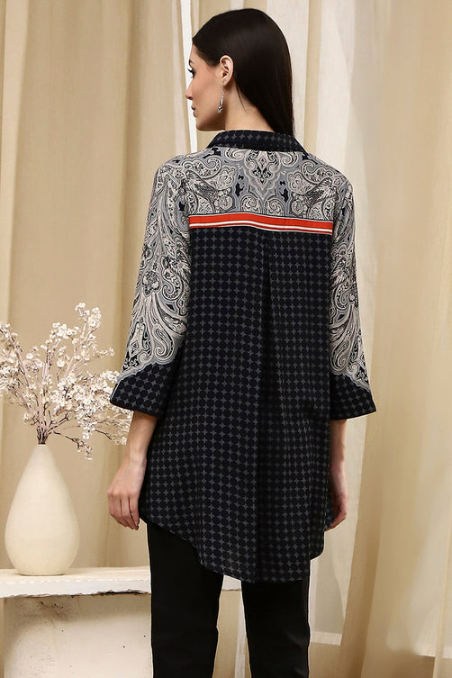 Woman wearing a black and white patterned shirt with a vase and flowers in the background