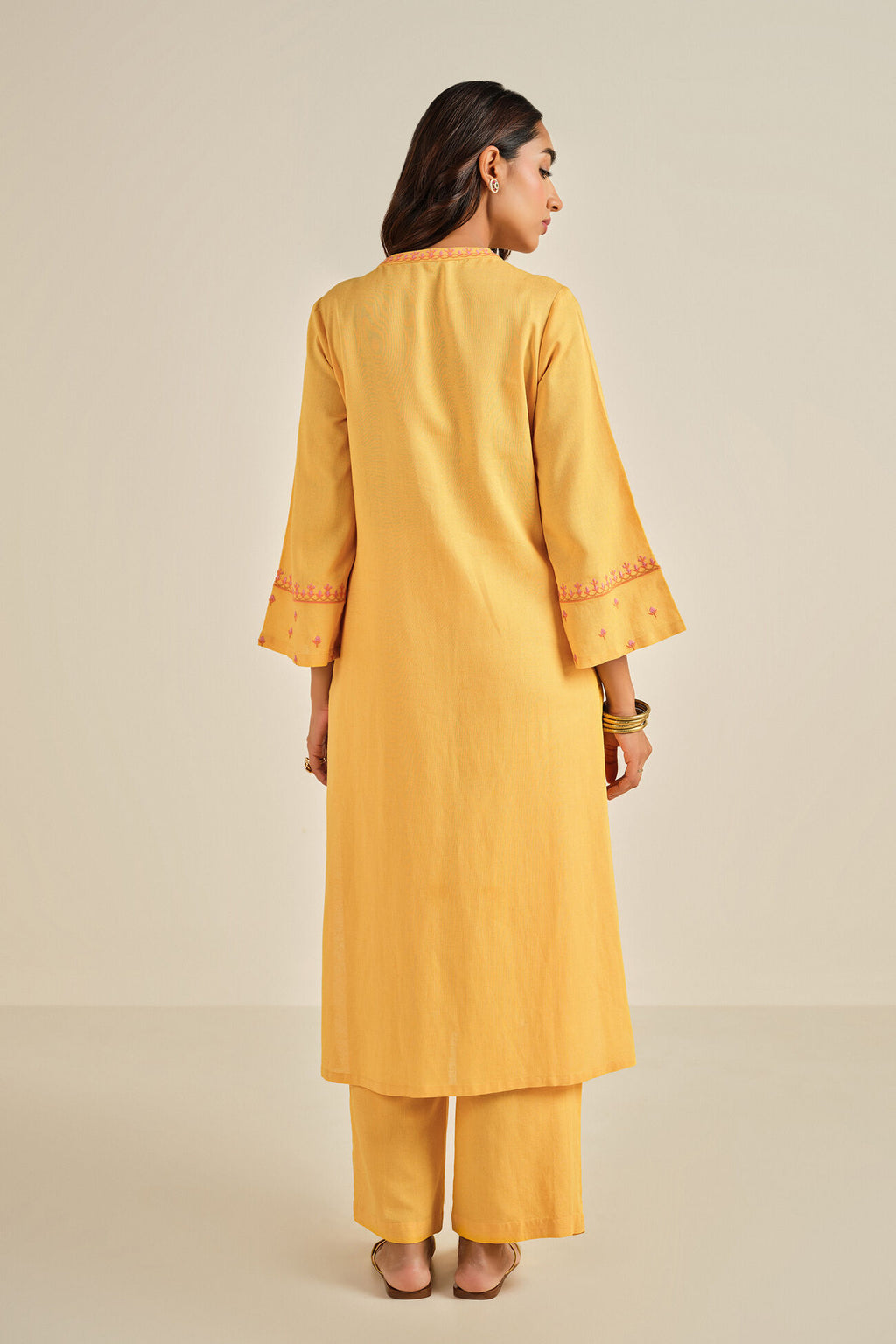 Woman wearing a yellow kurta with pants on a beige background