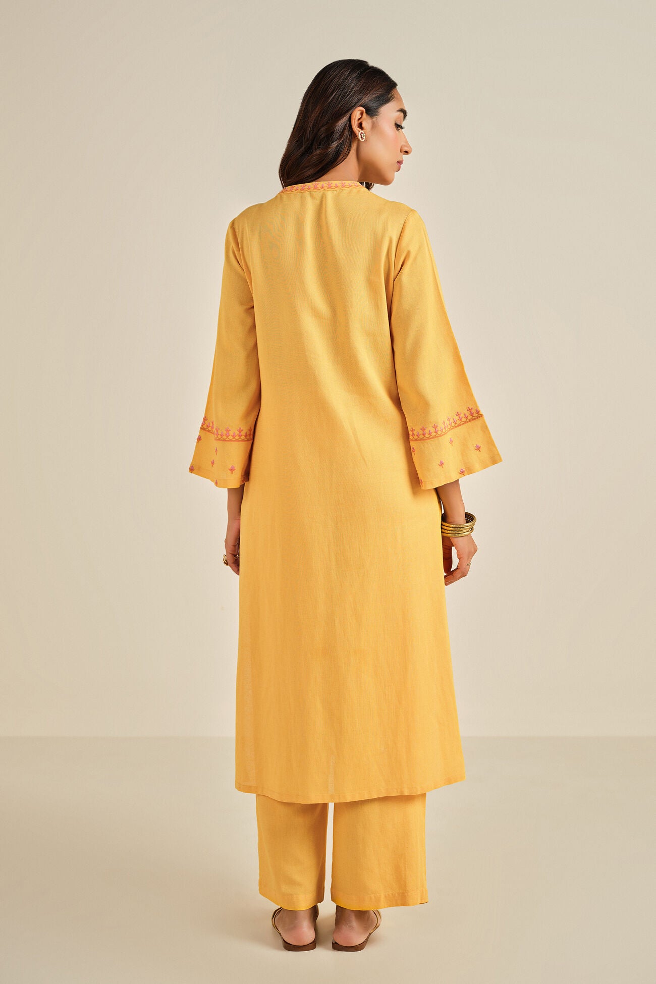 Woman wearing a yellow kurta with pants on a beige background