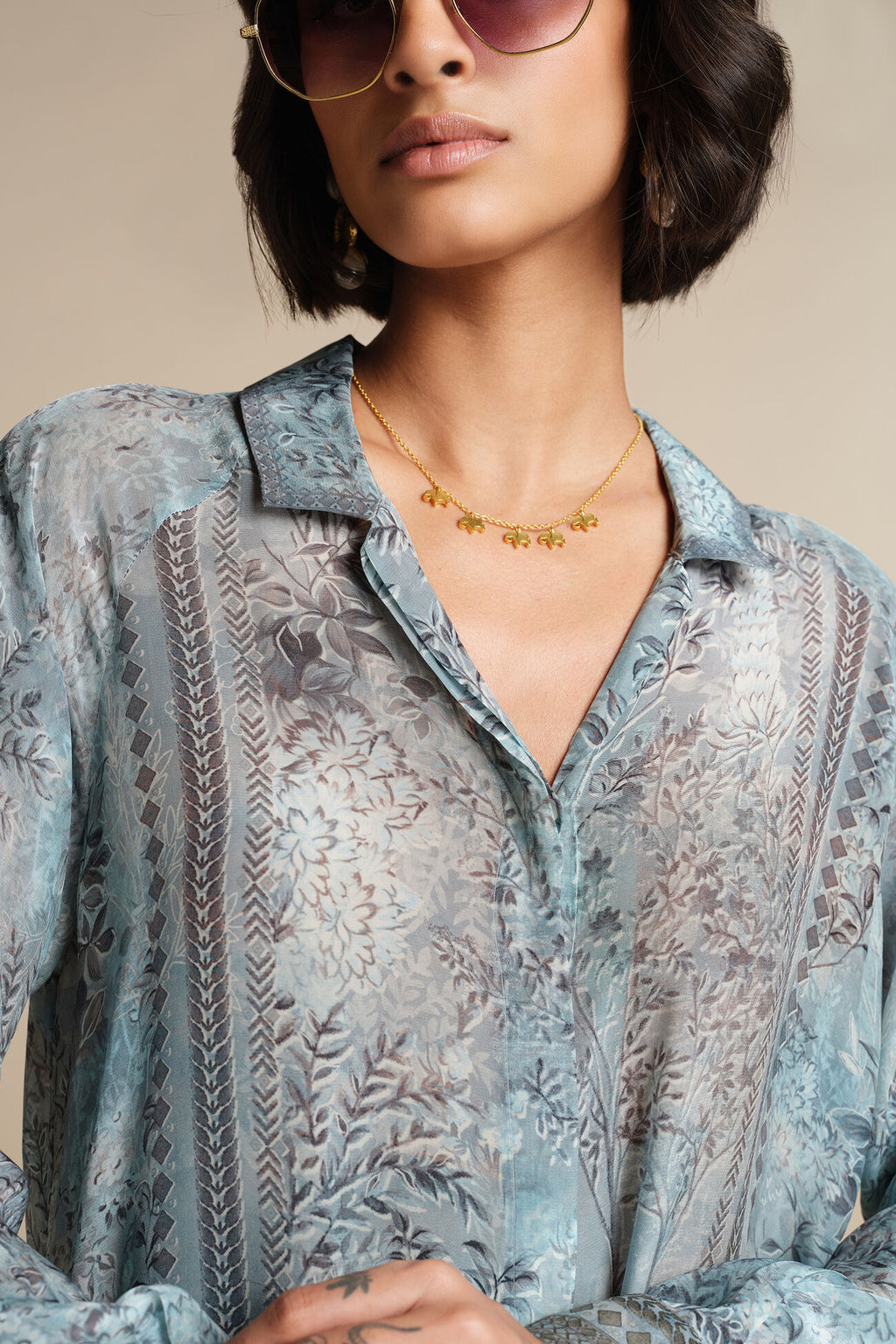 Person wearing a patterned shirt with a neutral background