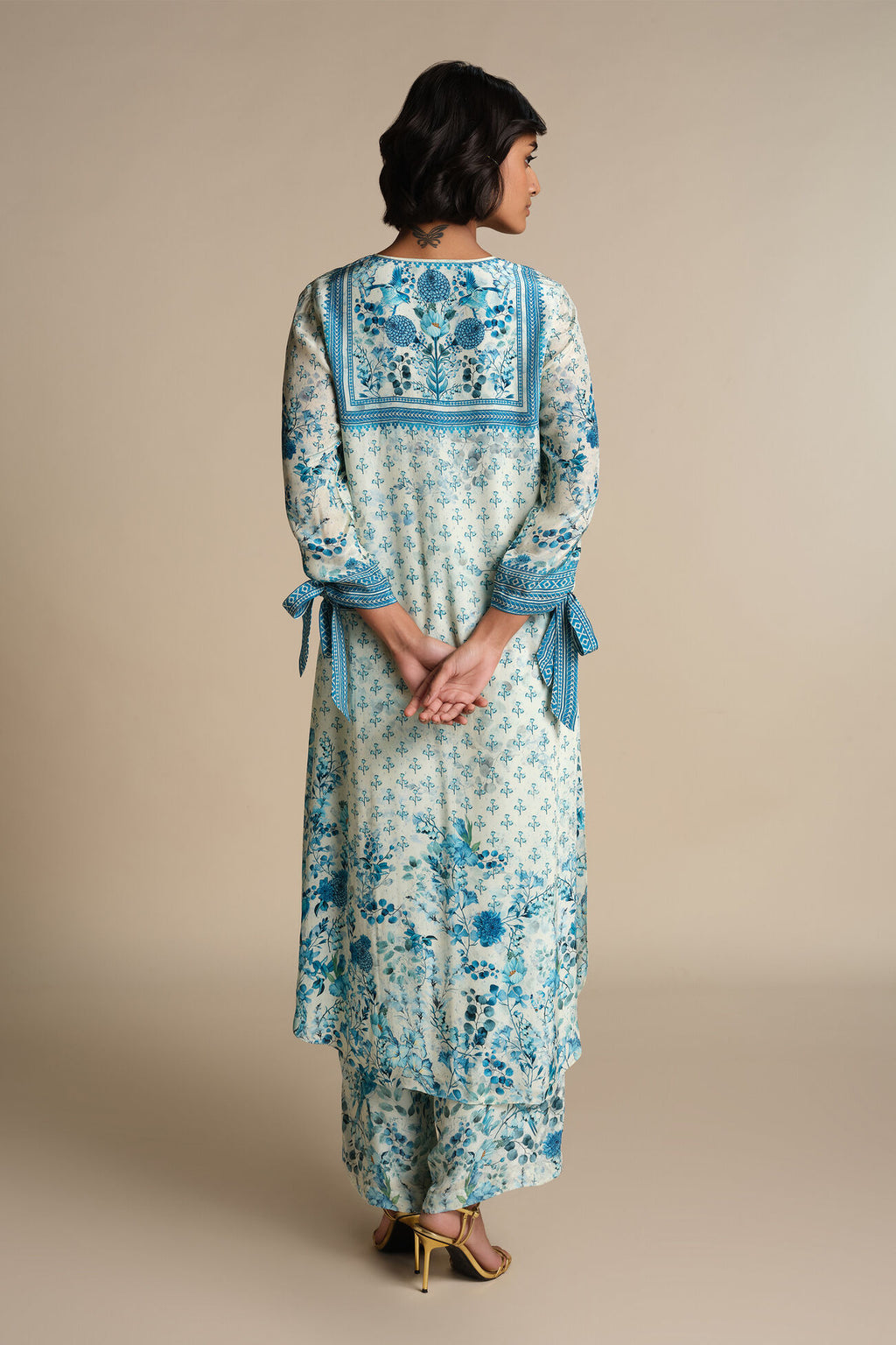 Woman wearing a floral dress with blue accents on a beige background