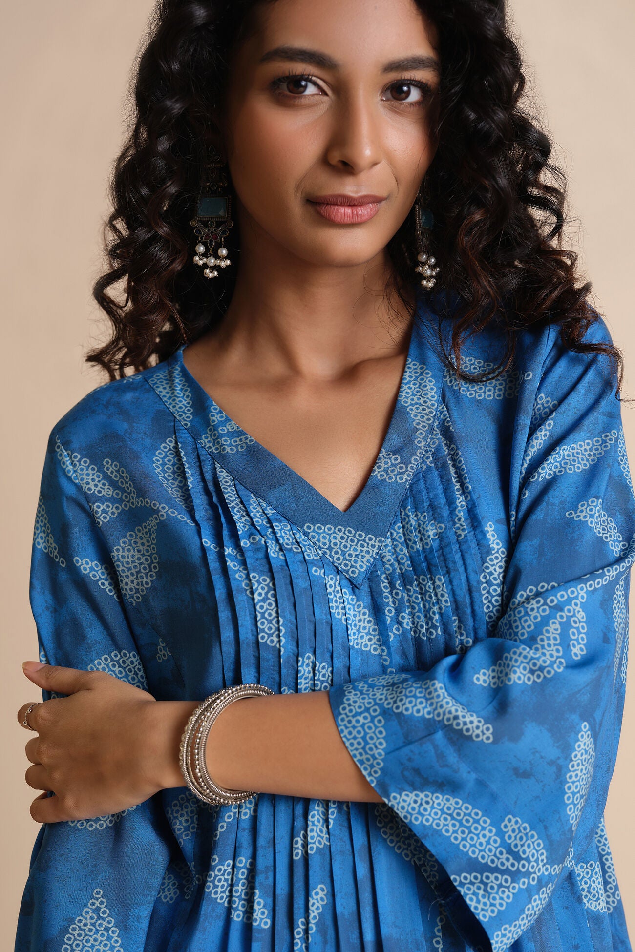 Woman wearing a blue patterned dress with a beige background