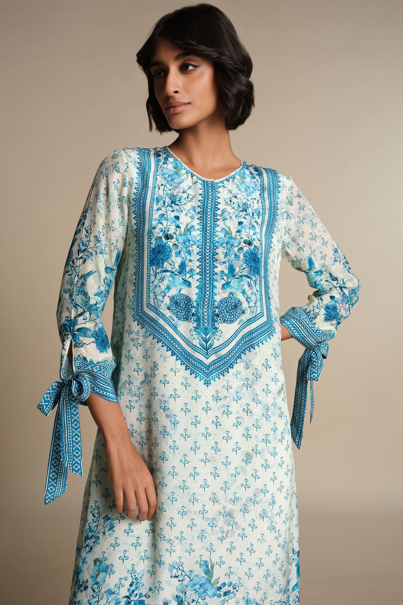 Woman wearing a blue and white floral embroidered dress against a neutral background