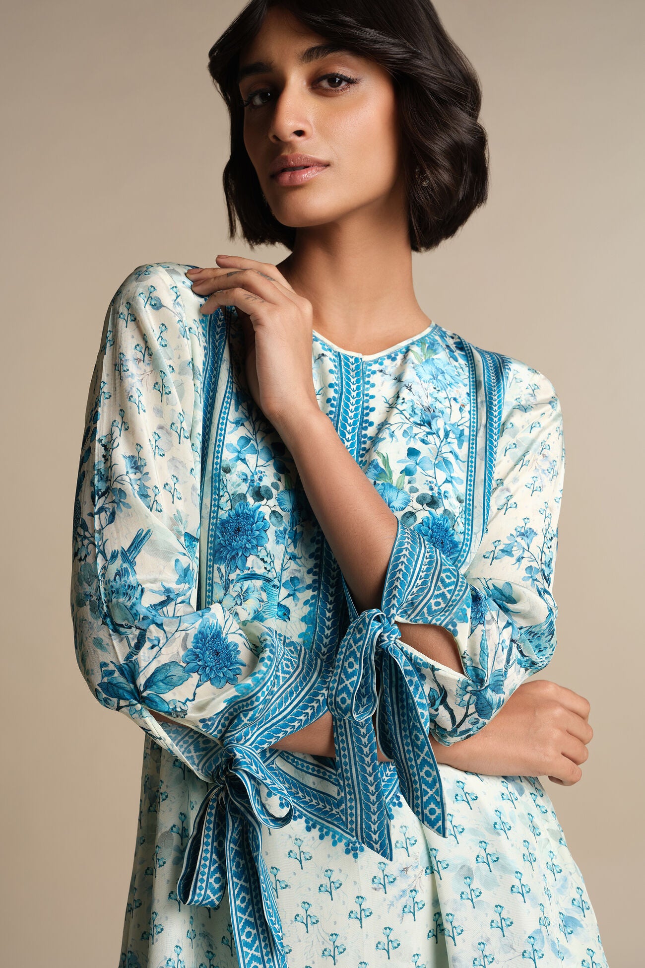 Woman wearing a blue and white floral dress with a beige background
