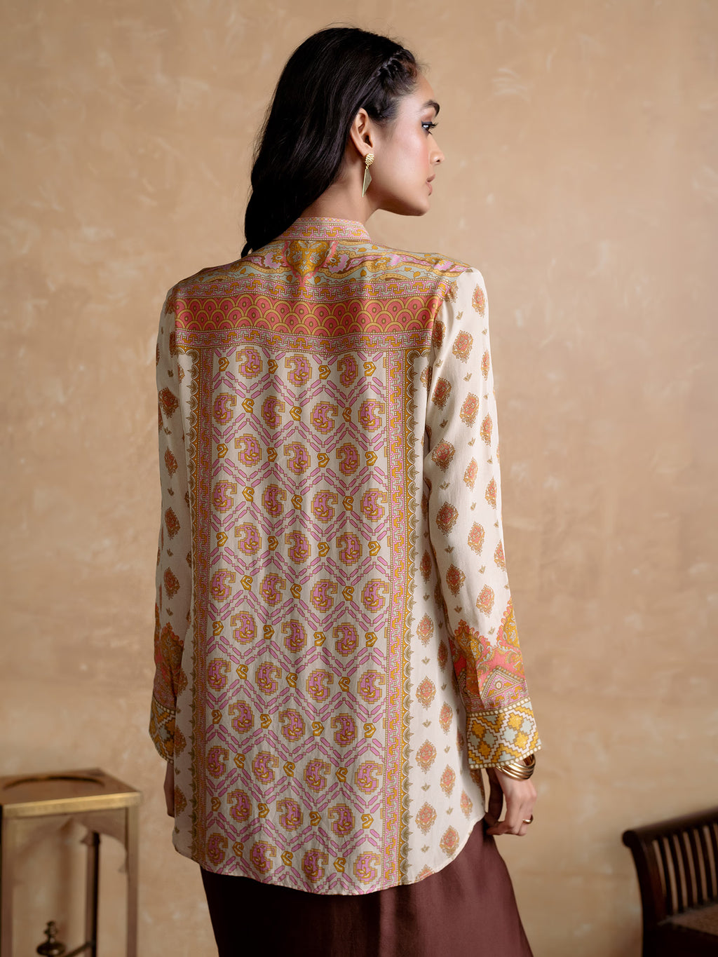 Woman wearing a patterned shirt with a beige background