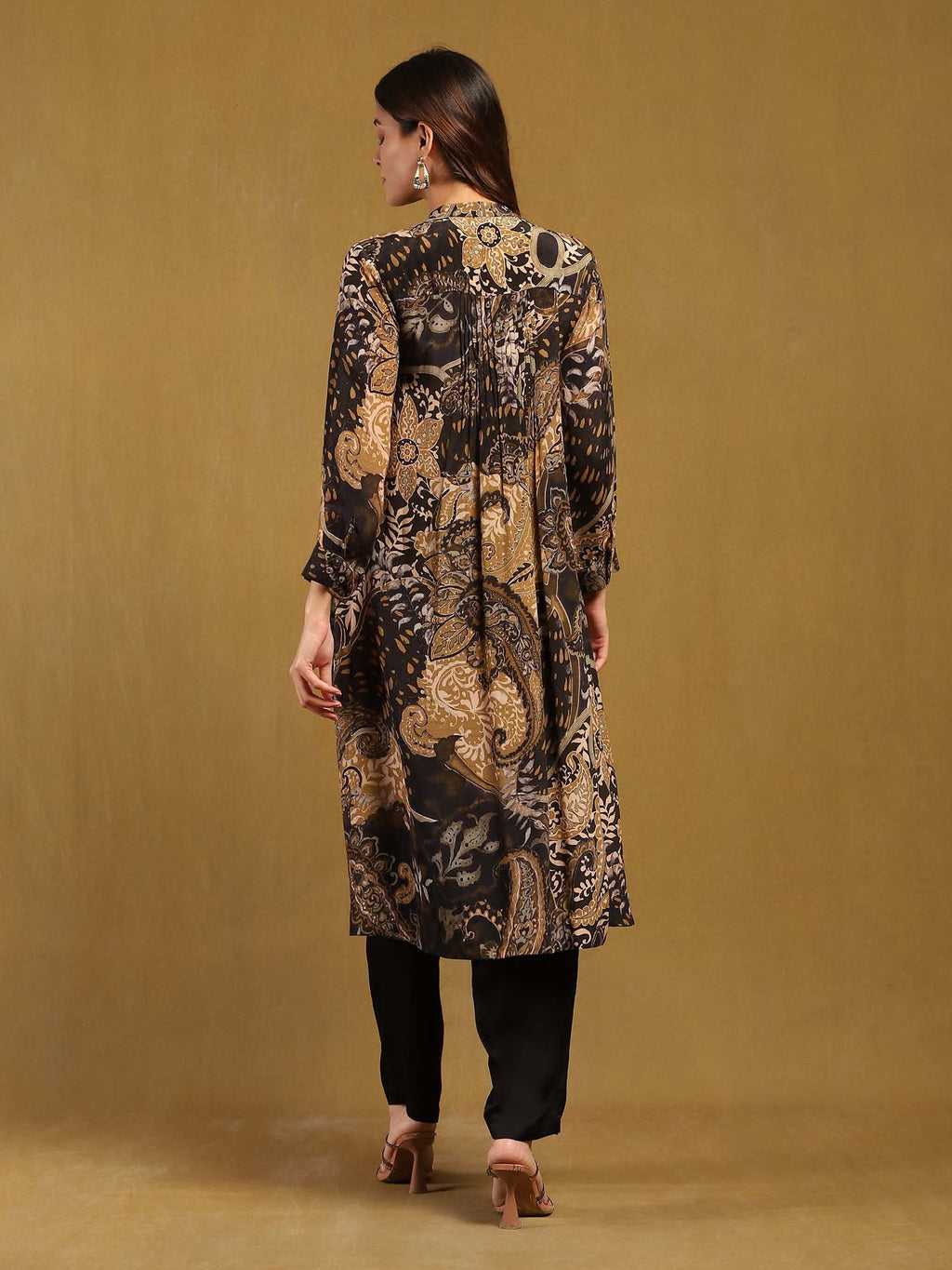 Woman wearing a long, patterned dress against a beige background