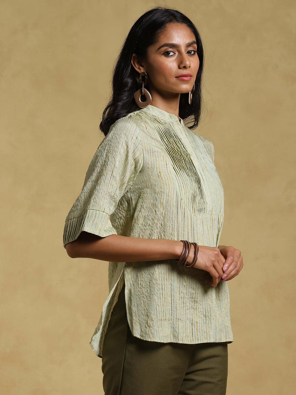Woman wearing a light green textured blouse against a beige background