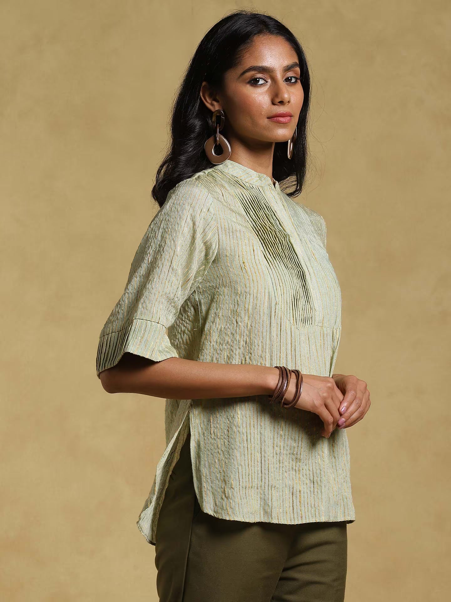 Woman wearing a light green textured blouse against a beige background