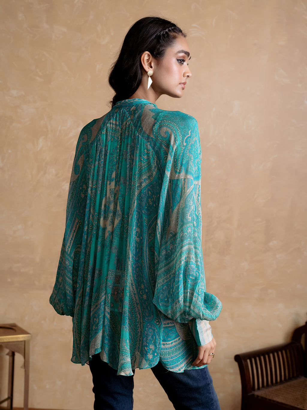 Woman wearing a Blue patterned Kurta against a beige wall.