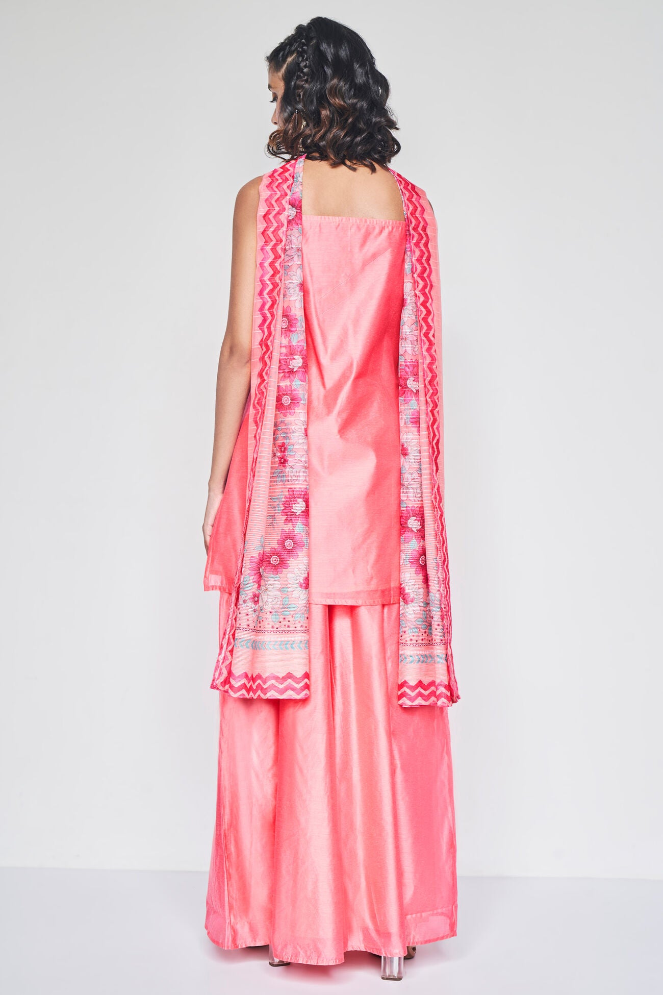 Woman wearing a pink traditional outfit with a matching dupatta on a white background