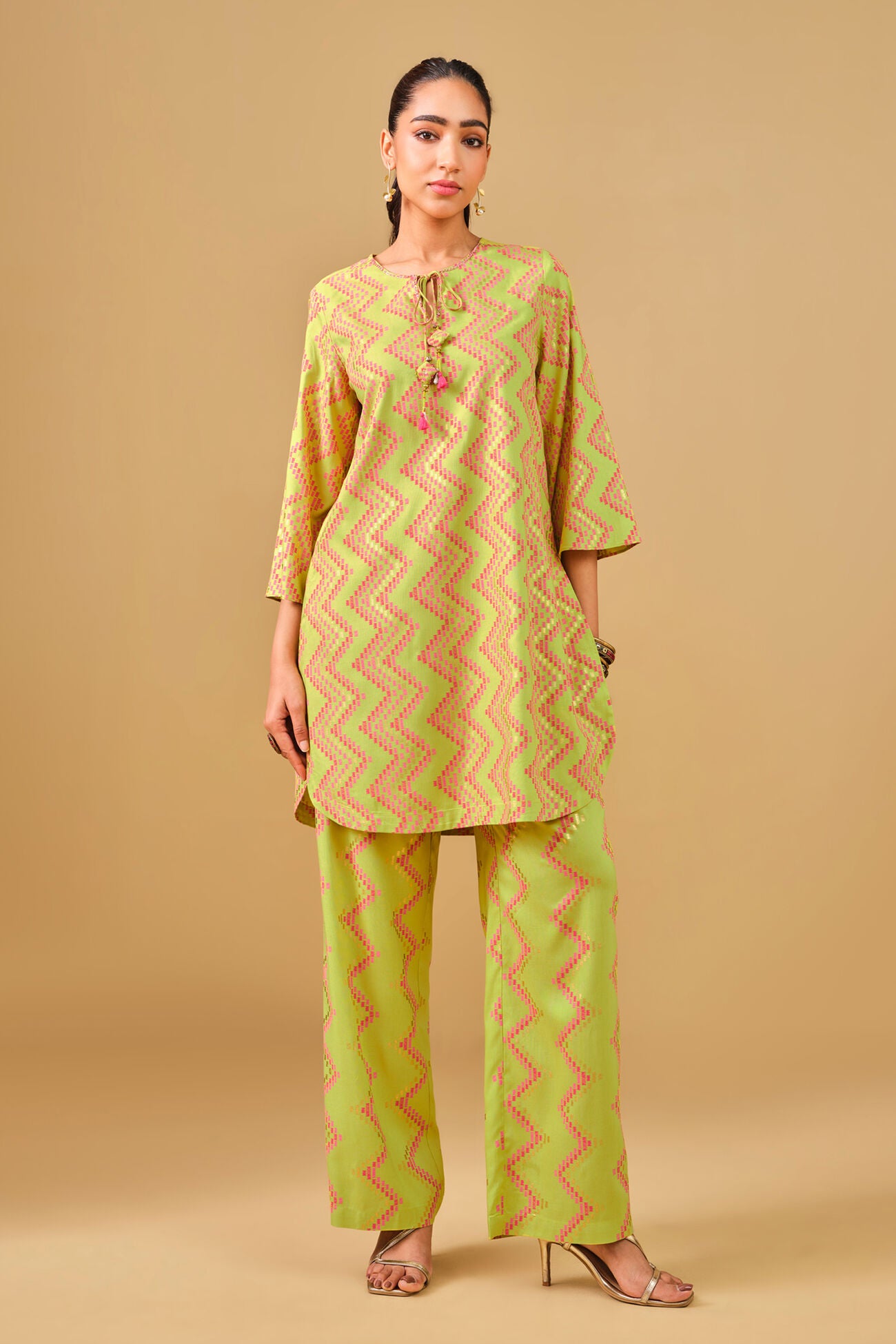 Woman wearing a green and beige zigzag patterned kurta with palazzo pants against a beige background