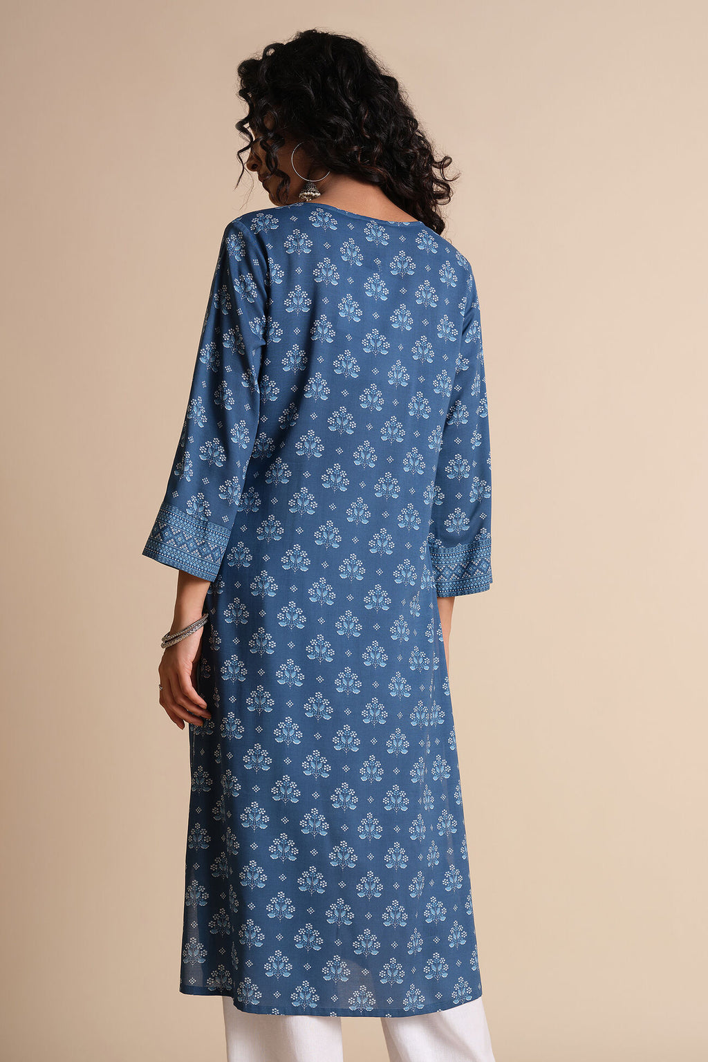 Woman wearing a blue patterned kurta against a beige background