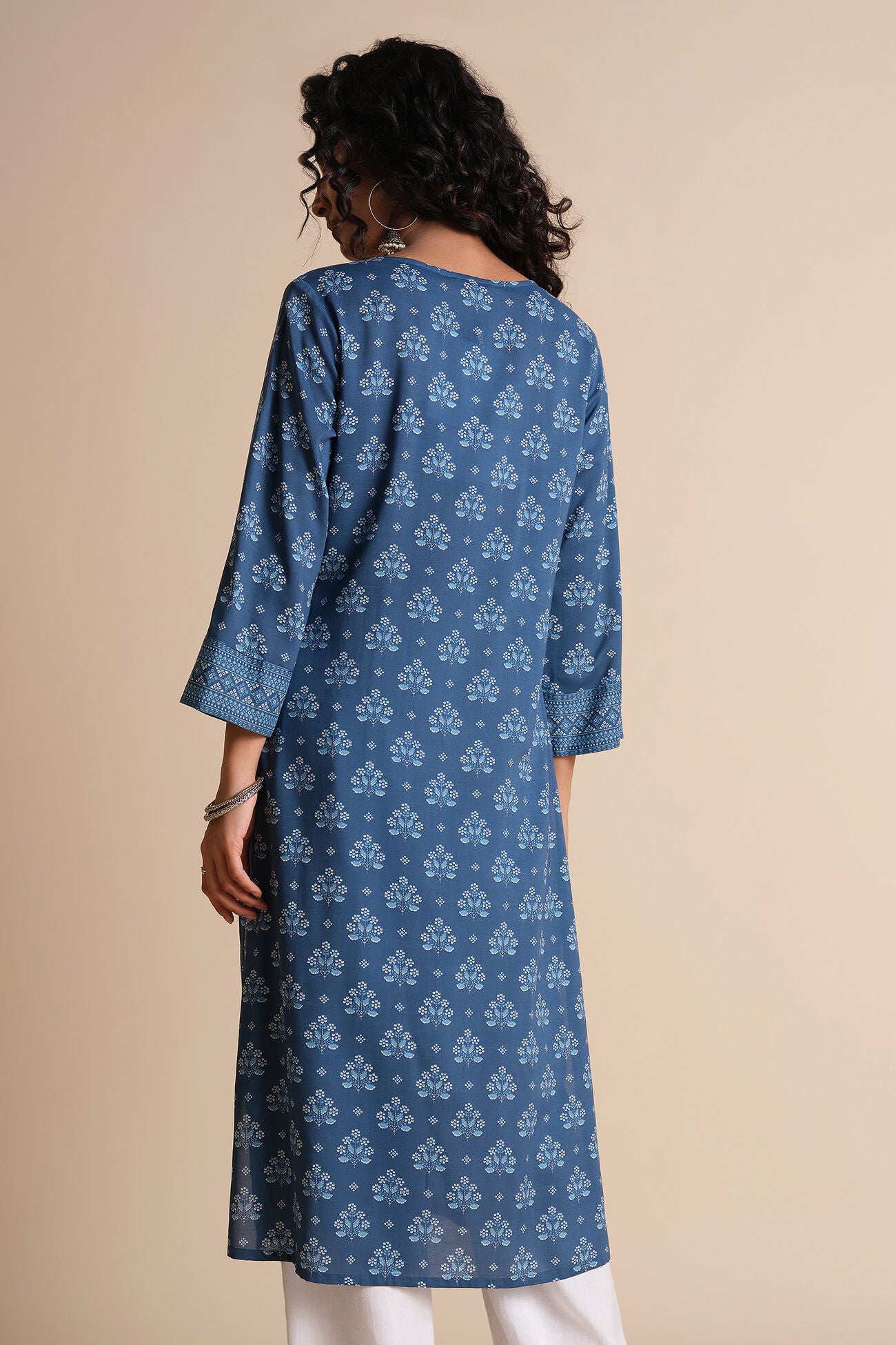 Woman wearing a blue patterned kurta against a beige background