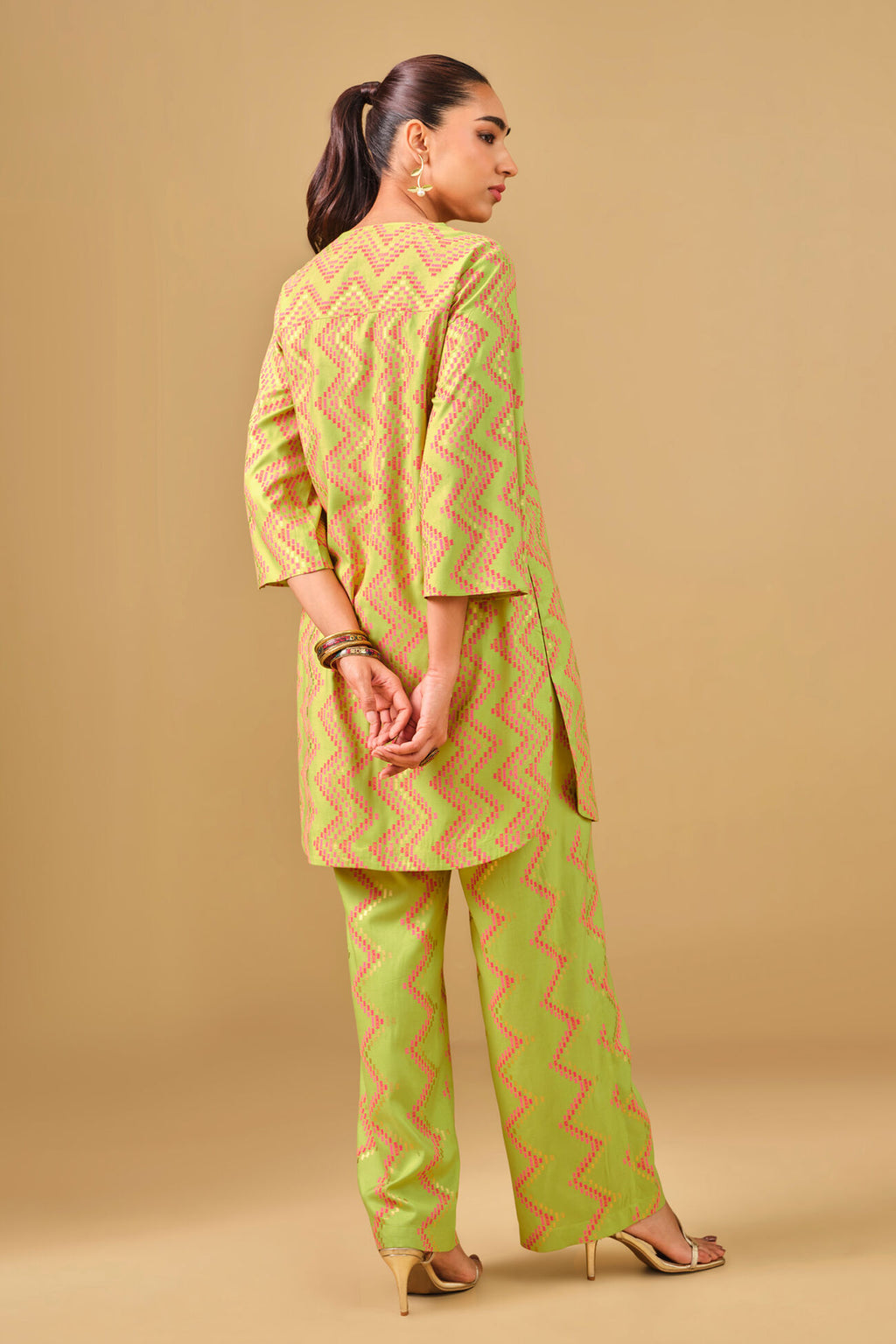 Woman wearing a yellow and green patterned kurta with pants on a beige background