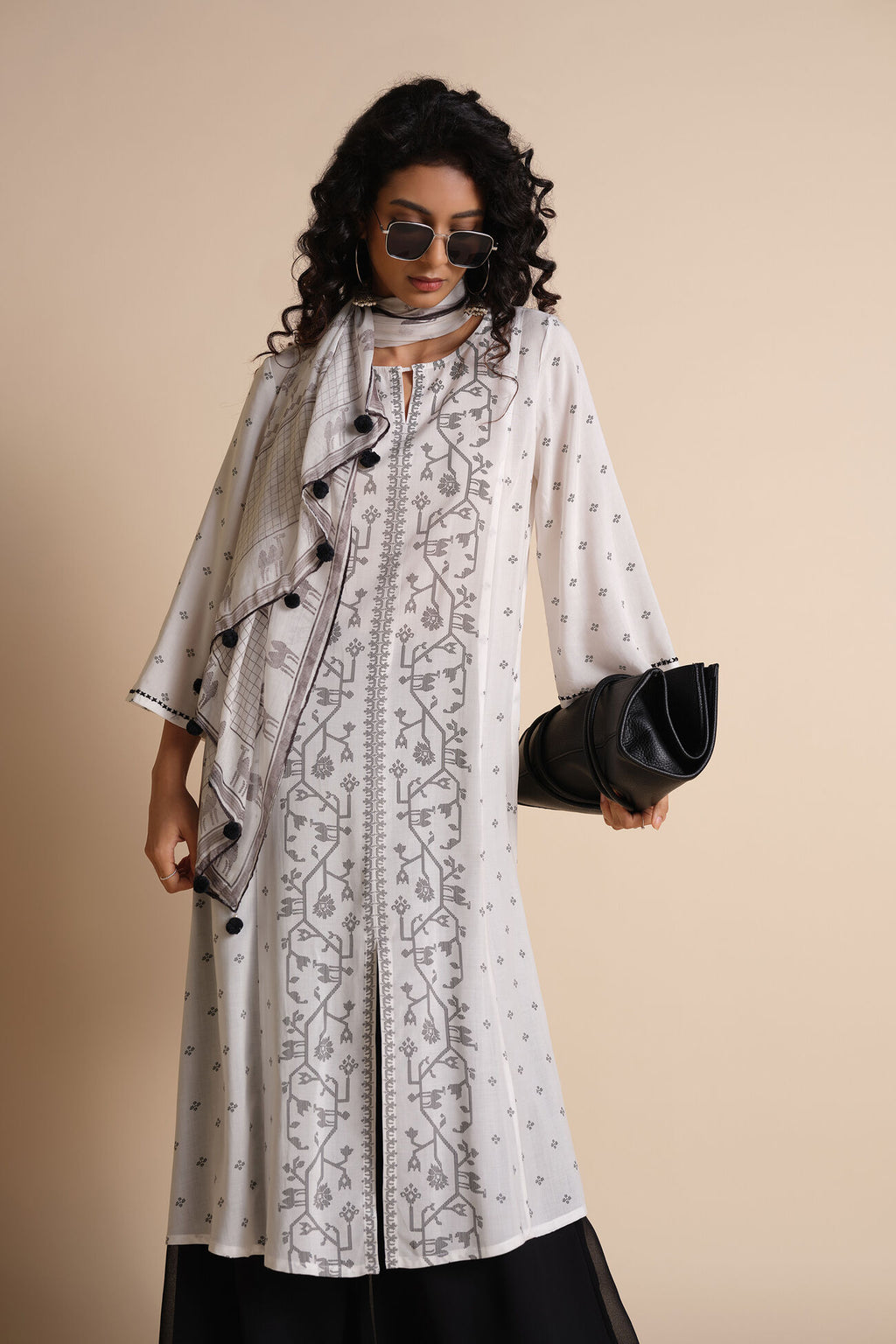 Woman wearing a long, patterned dress with black buttons against a beige background