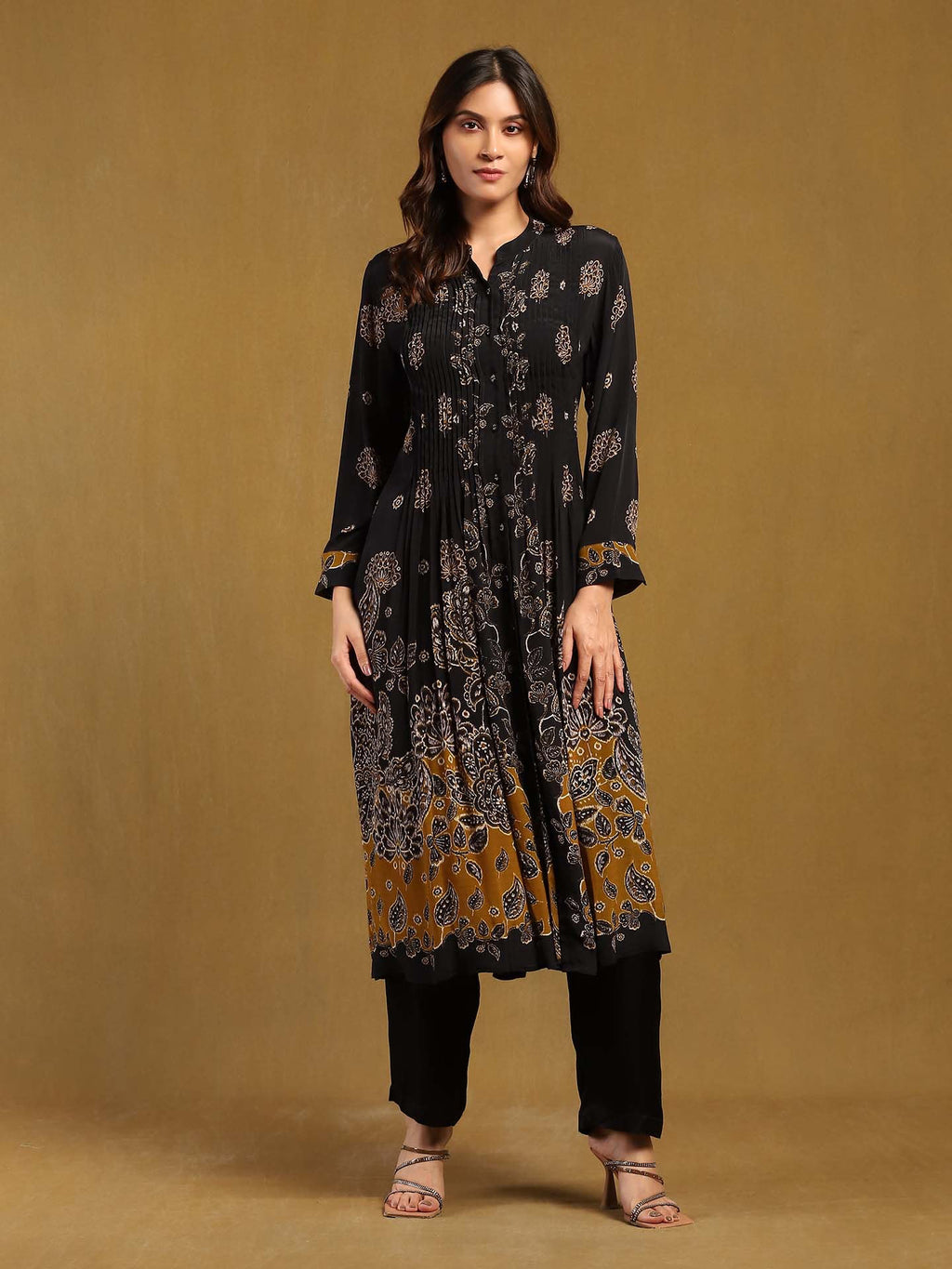 Woman wearing a black and gold patterned outfit on a brown background