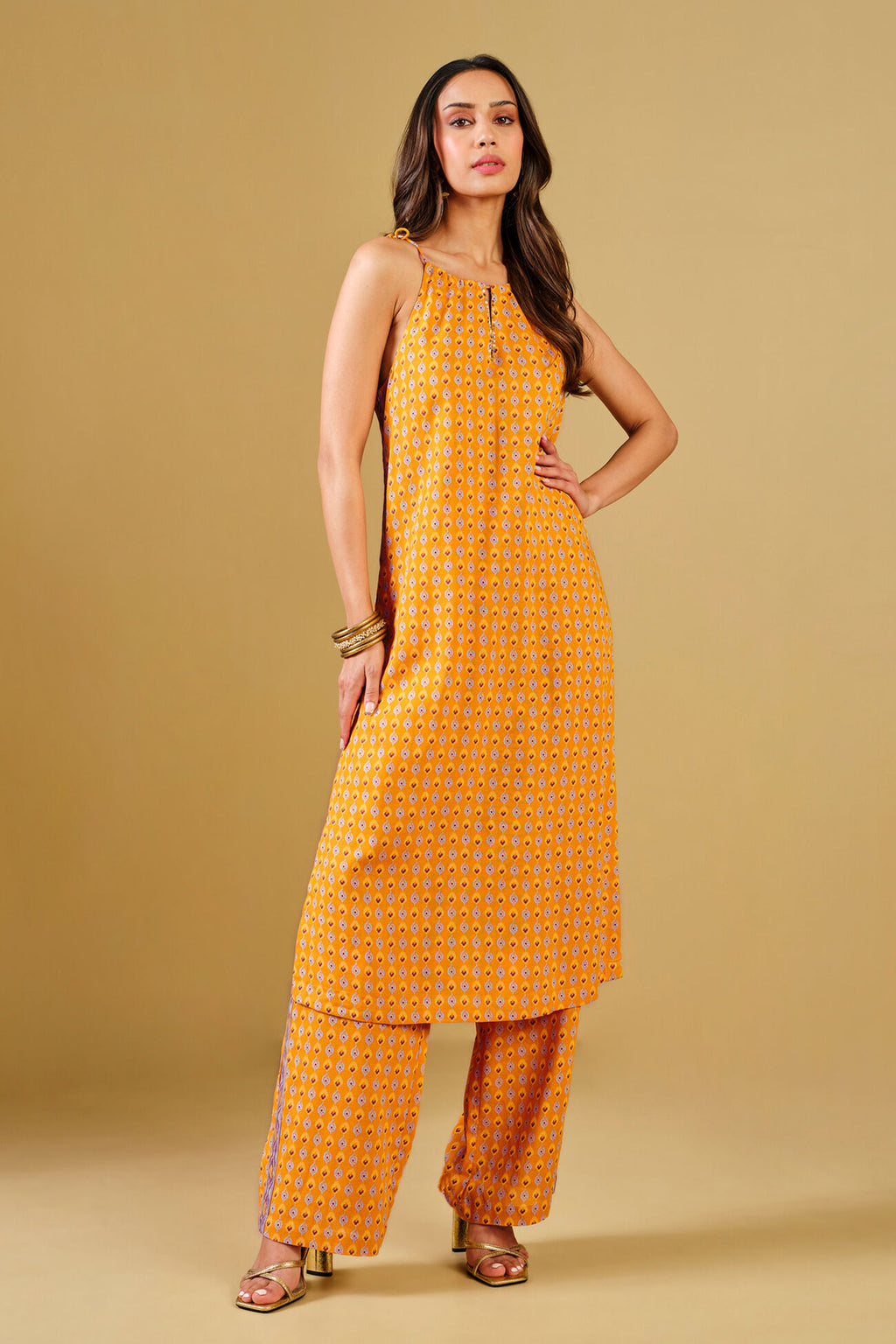 Woman wearing an Yellow patterned outfit on a beige background