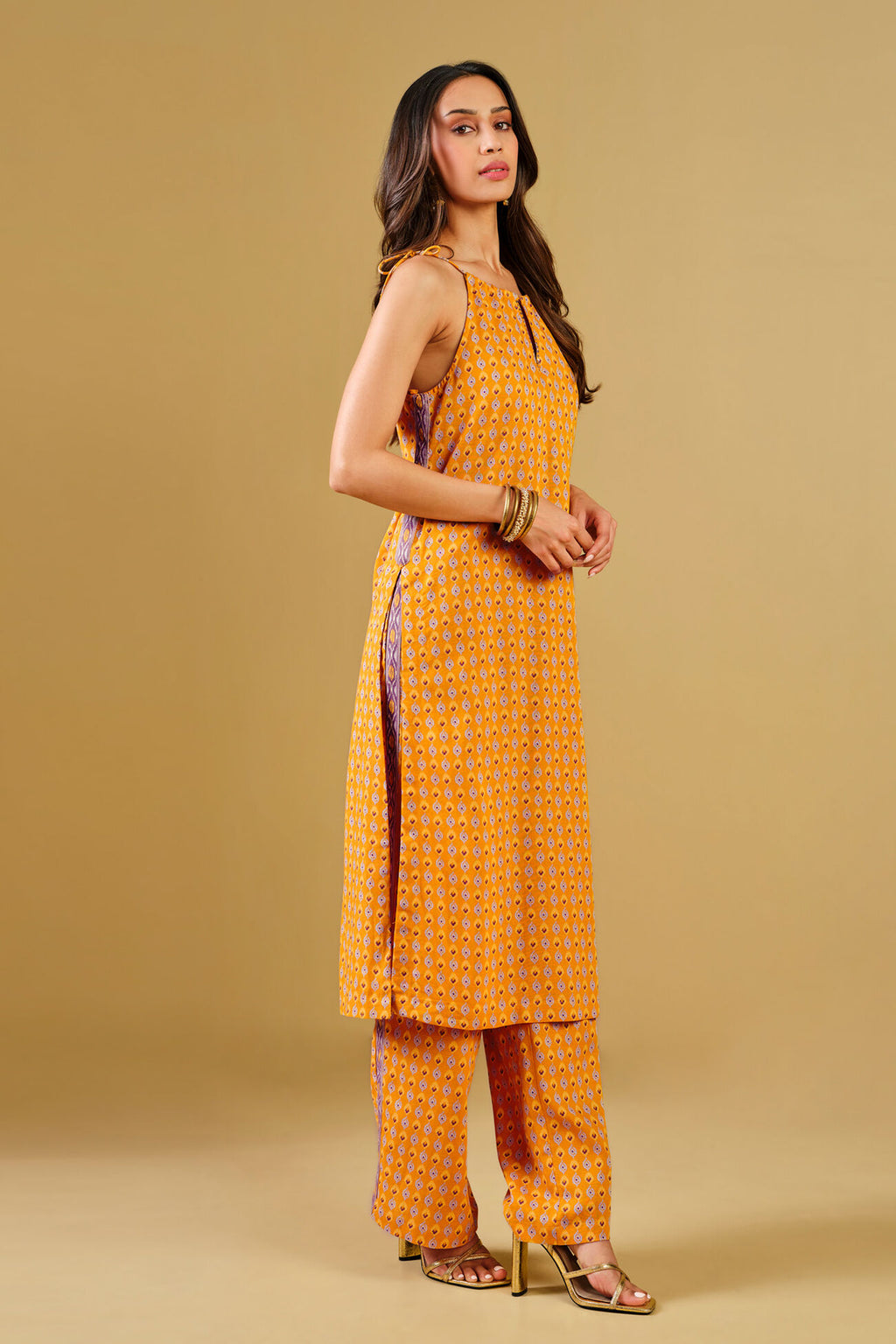 Woman wearing a yellow patterned outfit on a beige background