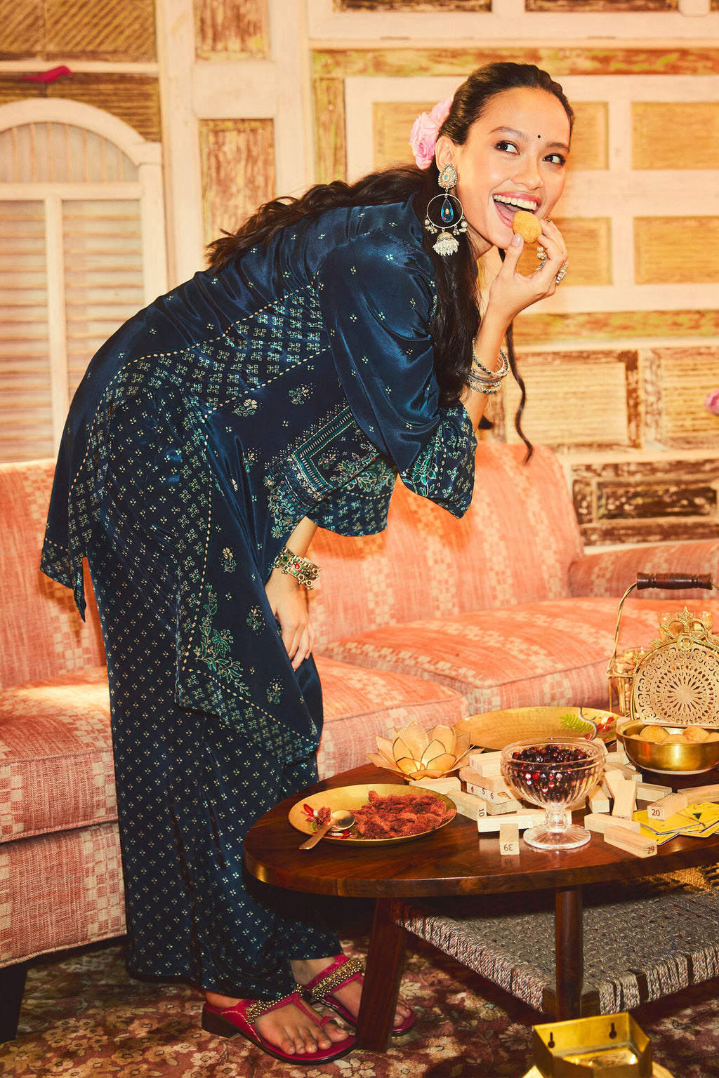 Woman in traditional attire eating from a plate in a decorated room.