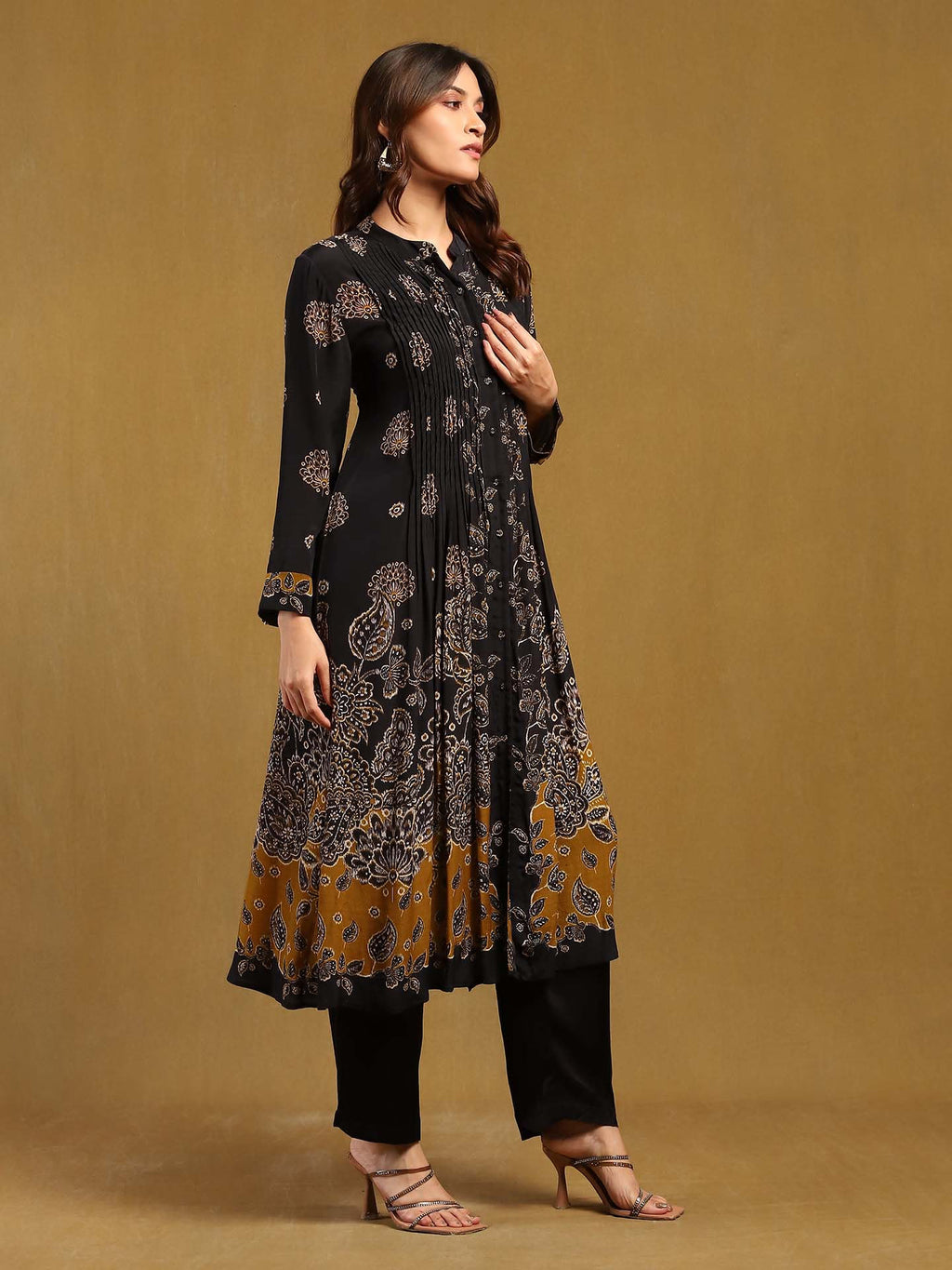 Woman wearing a black and gold patterned dress against a brown background