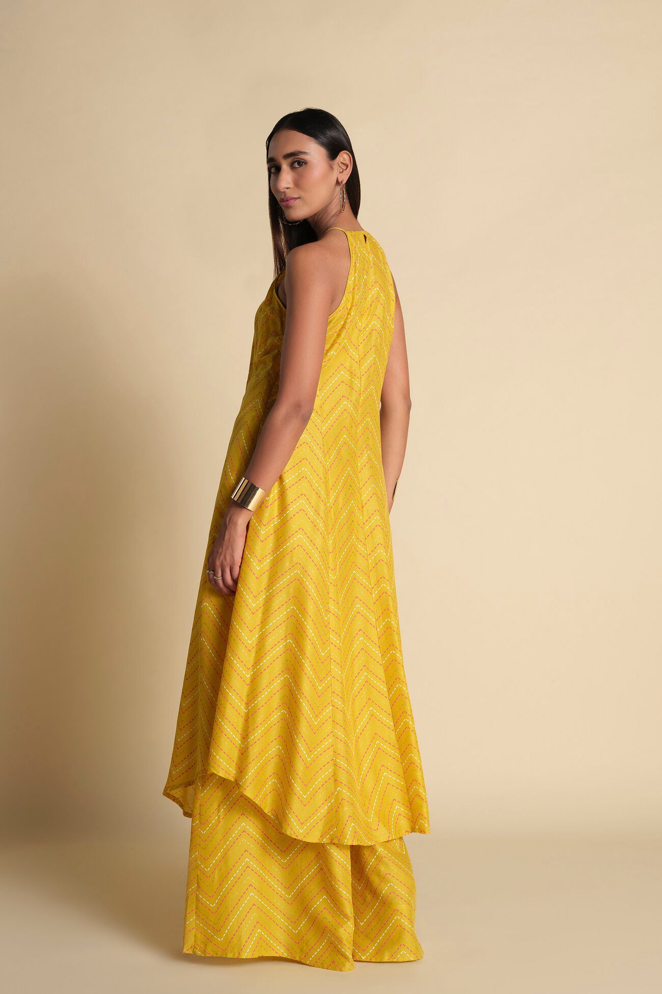 Woman wearing a yellow dress with a textured pattern on a beige background