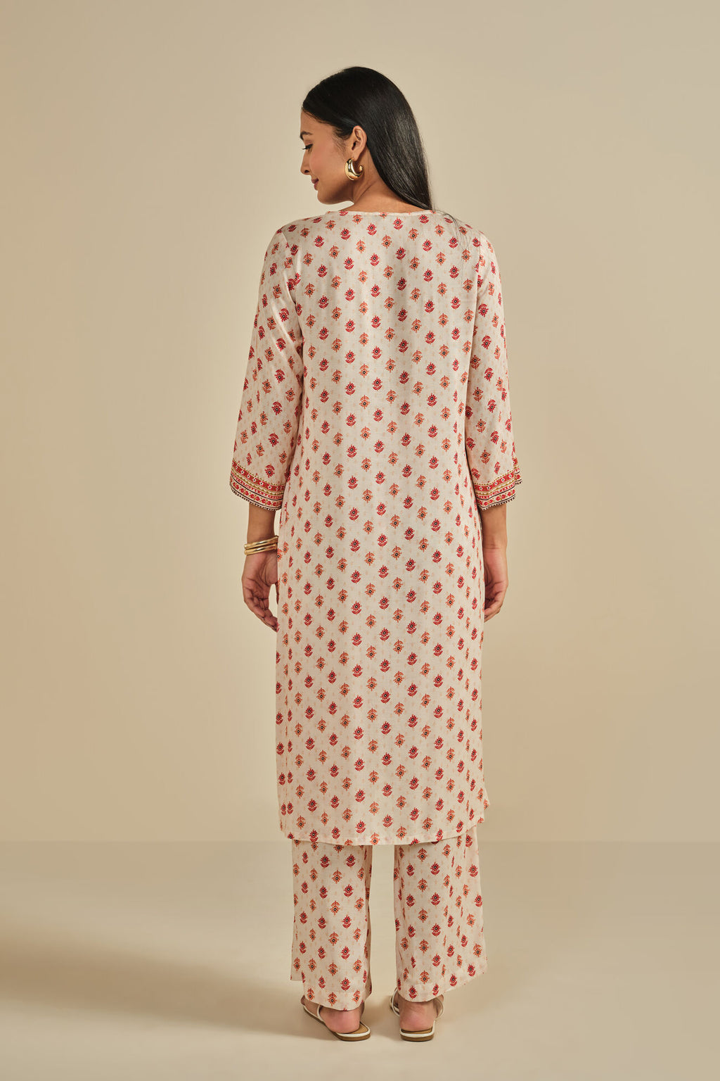 Woman wearing a patterned kurta with pants on a beige background
