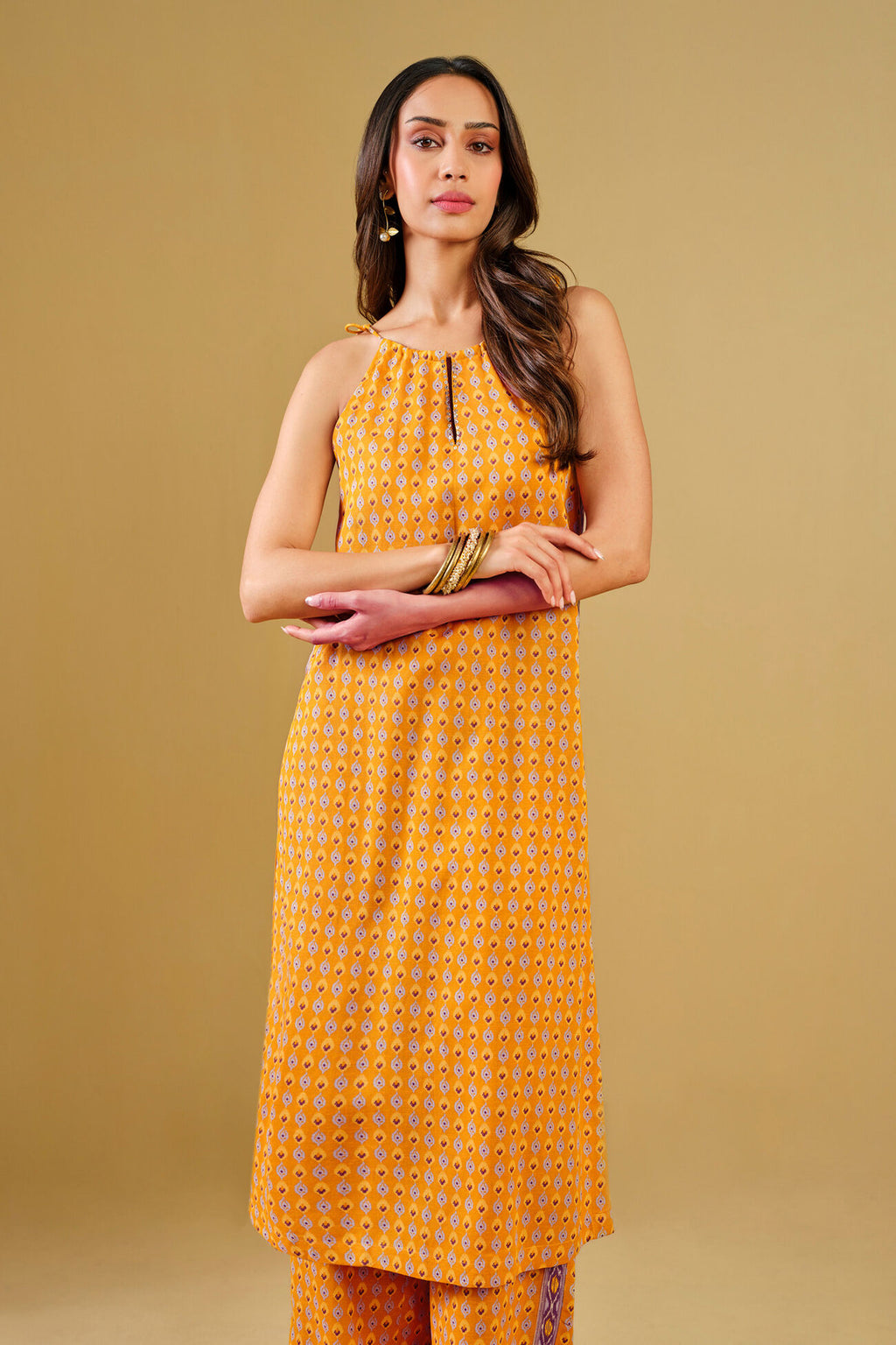 Woman wearing a yellow patterned dress against a beige background