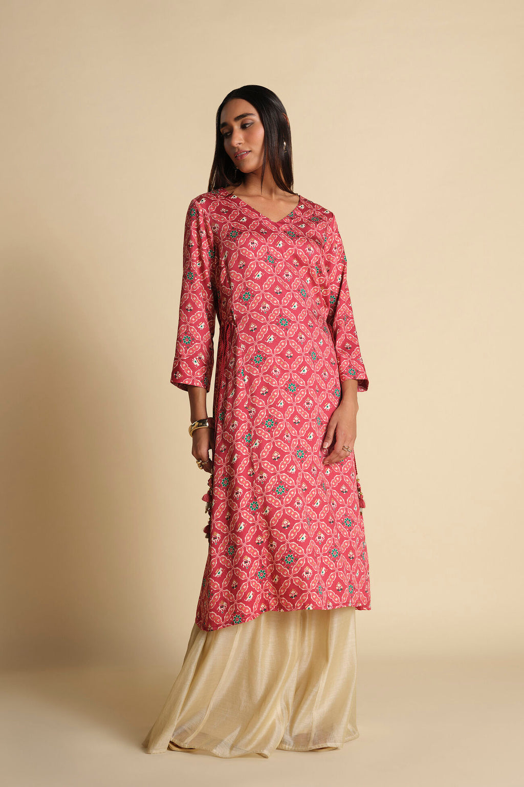 Woman wearing a pink patterned kurta with beige pants against a beige background