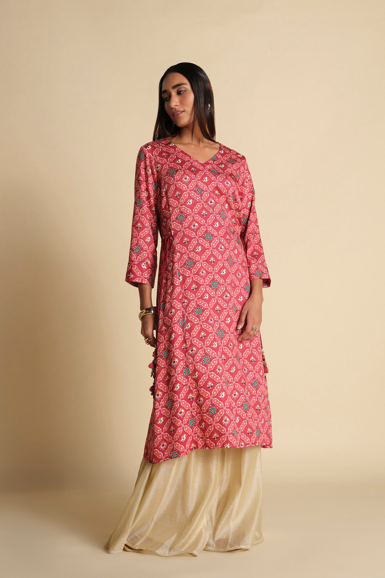 Woman wearing a pink patterned kurta with beige pants against a beige background