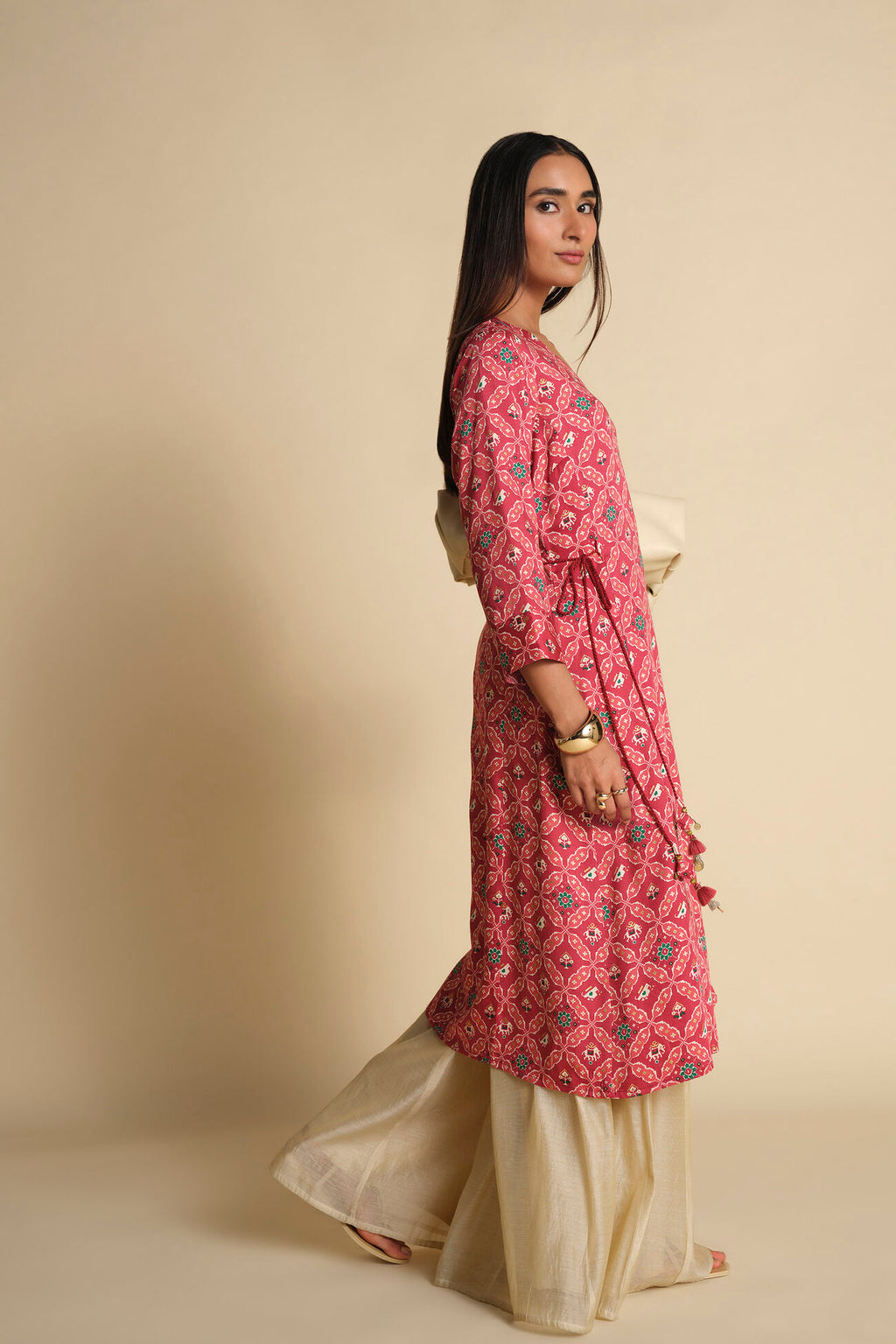 Woman wearing a pink floral kurta with beige pants against a beige background